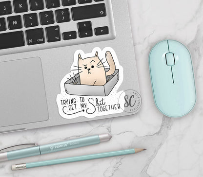 a sticker of a cat in a box on a laptop