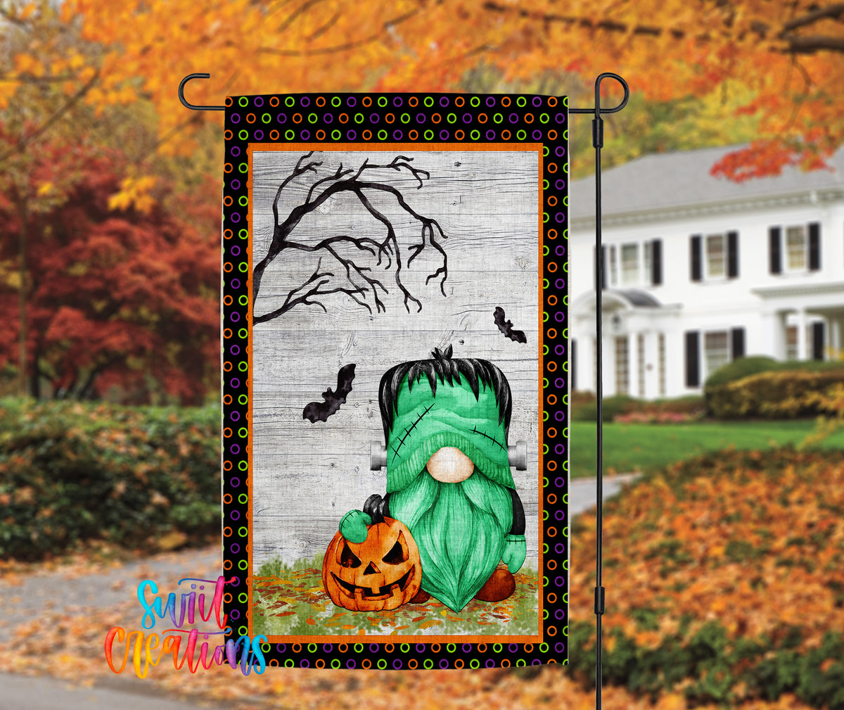 A Halloween-themed garden flag featuring a green gnome holding a jack-o-lantern, with a spooky tree and bats in the background.