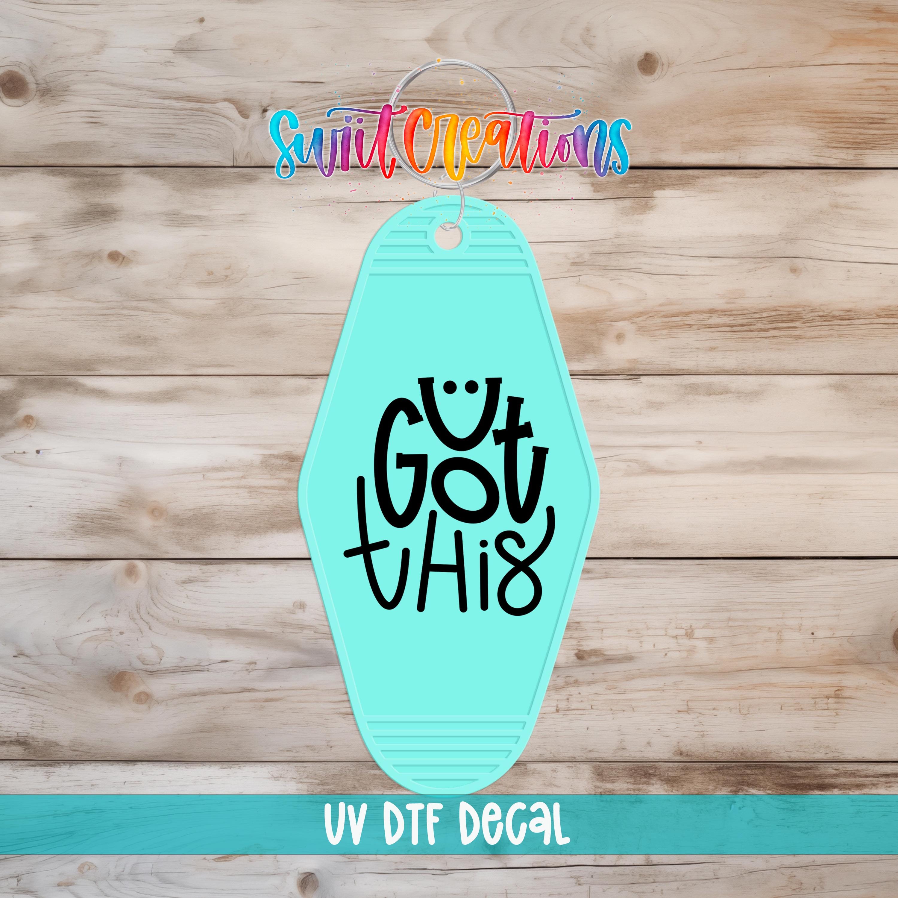 A turquoise keychain with the text "Got this" printed on it, placed on a wooden surface.