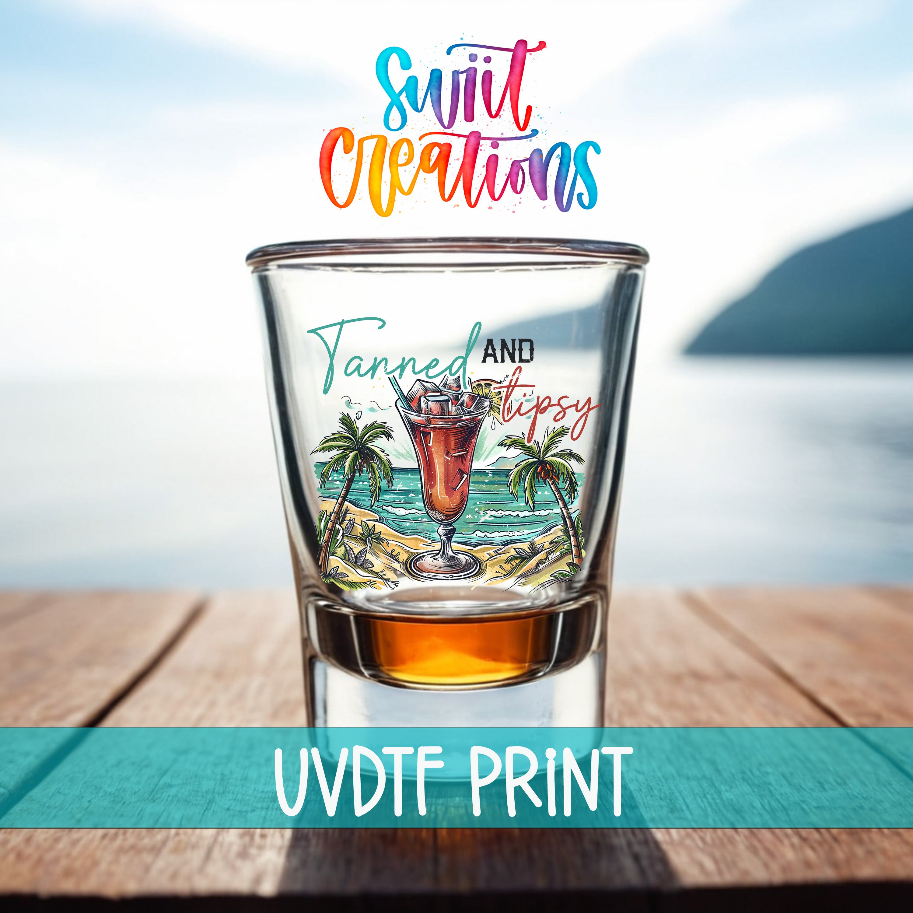 A colorful shot glass with a tropical beach scene and a cocktail illustration, placed on a wooden surface with a body of water in the background.