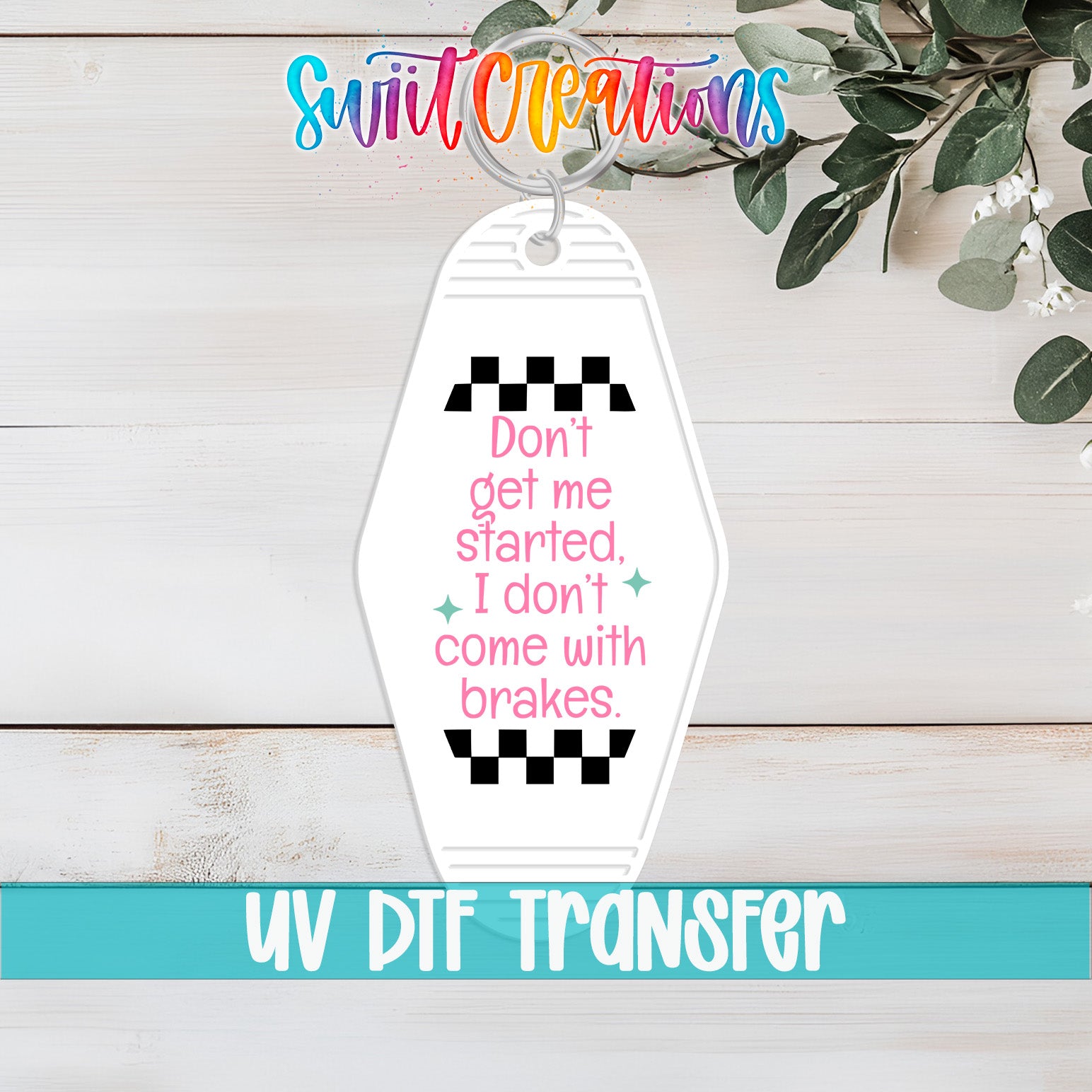 A keychain with a humorous message printed on it, placed on a wooden surface with some greenery in the background.