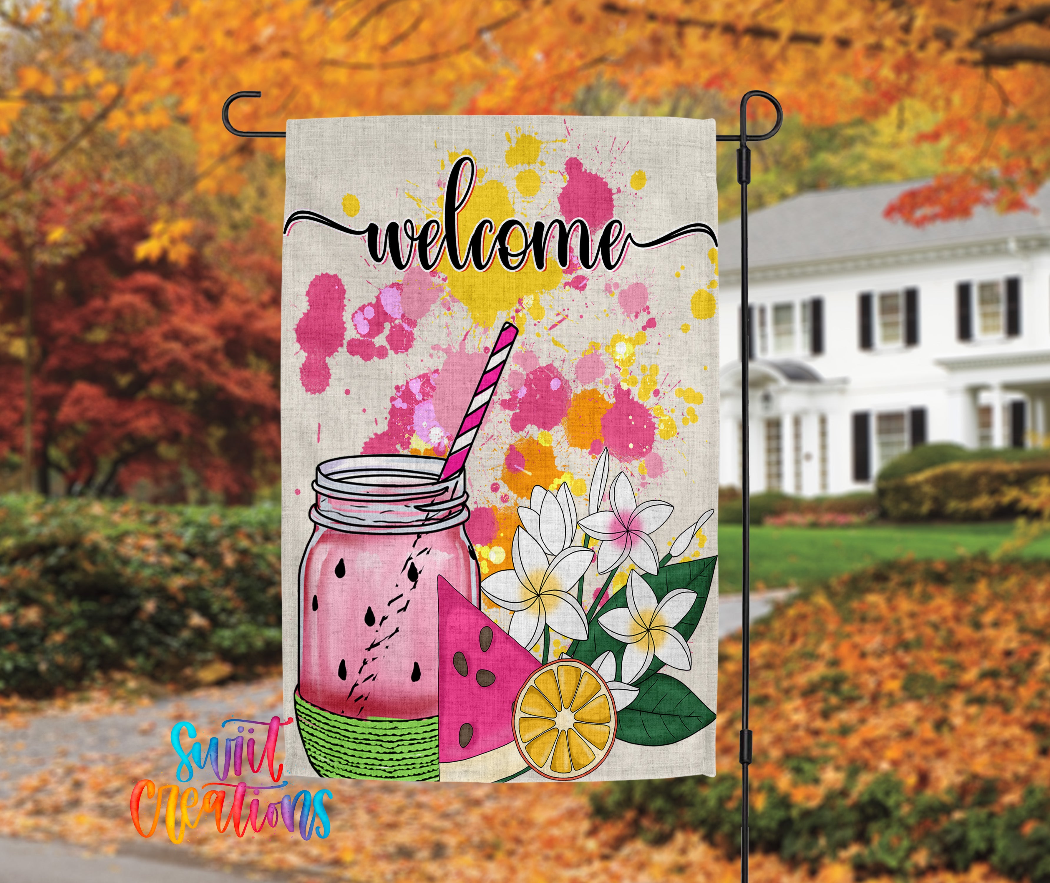 A colorful welcome sign featuring a mason jar with a straw, watermelon slices, and flowers, set against a backdrop of autumn foliage.