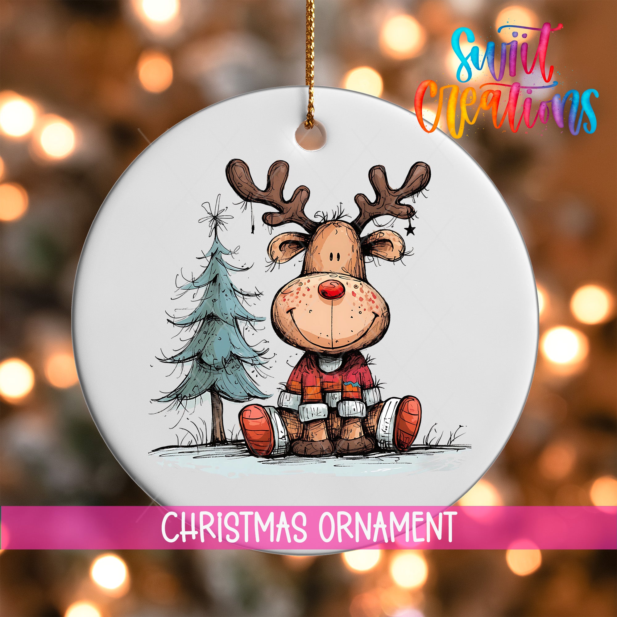 A white Christmas ornament featuring a cartoon reindeer sitting next to a Christmas tree.