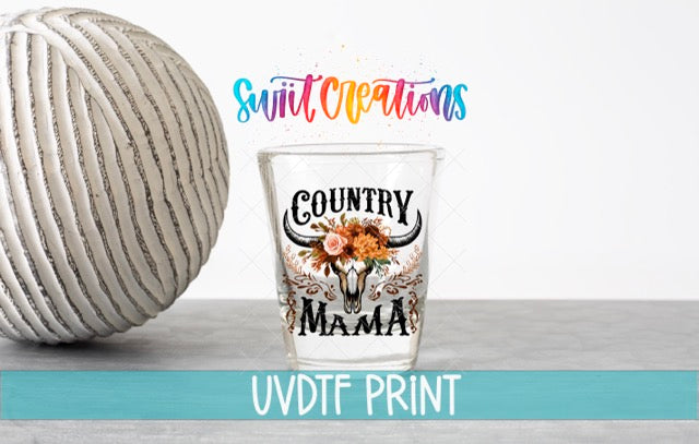 a shot glass sitting next to a ball of yarn