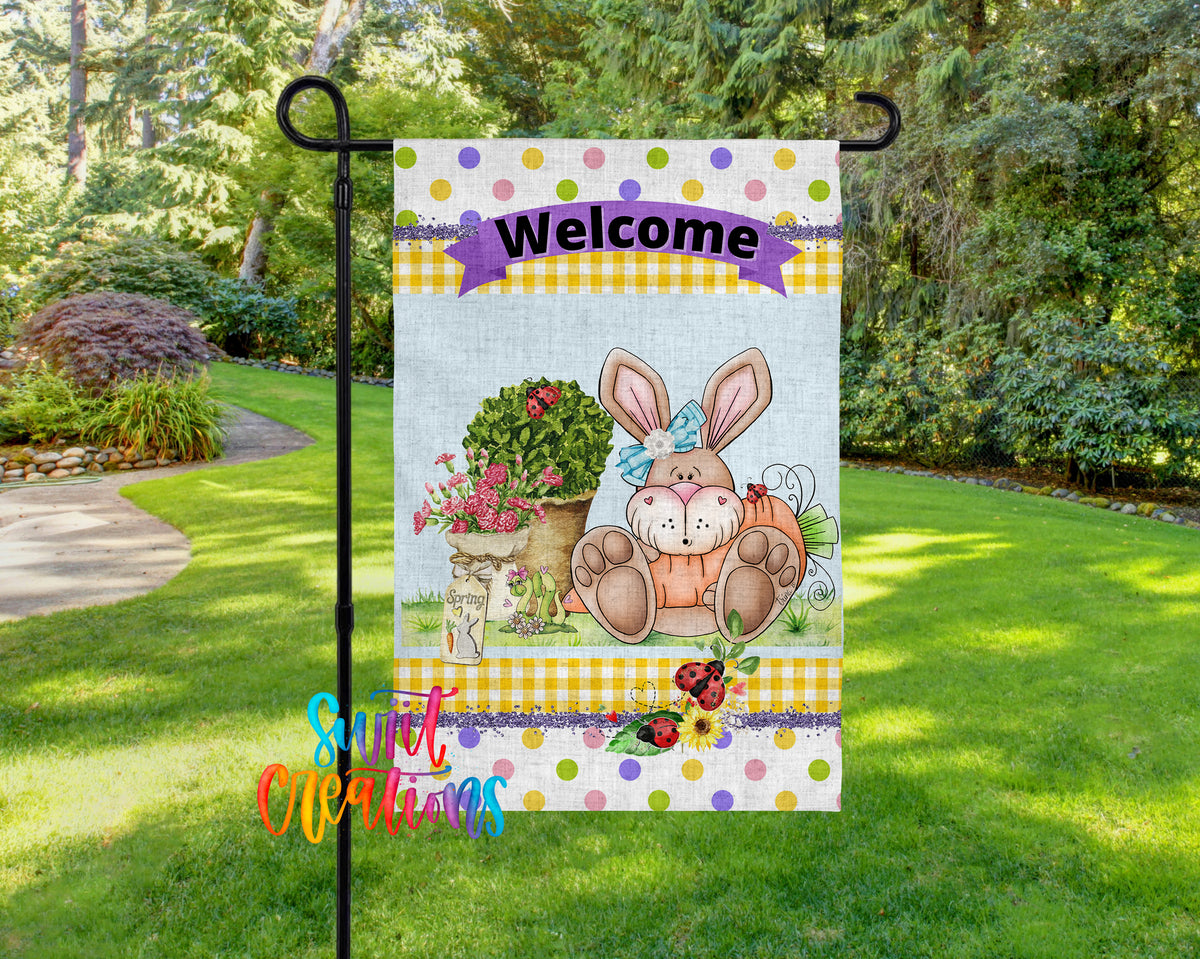 A colorful garden sign featuring a cartoon rabbit and flowers, with the word "Welcome" displayed prominently.