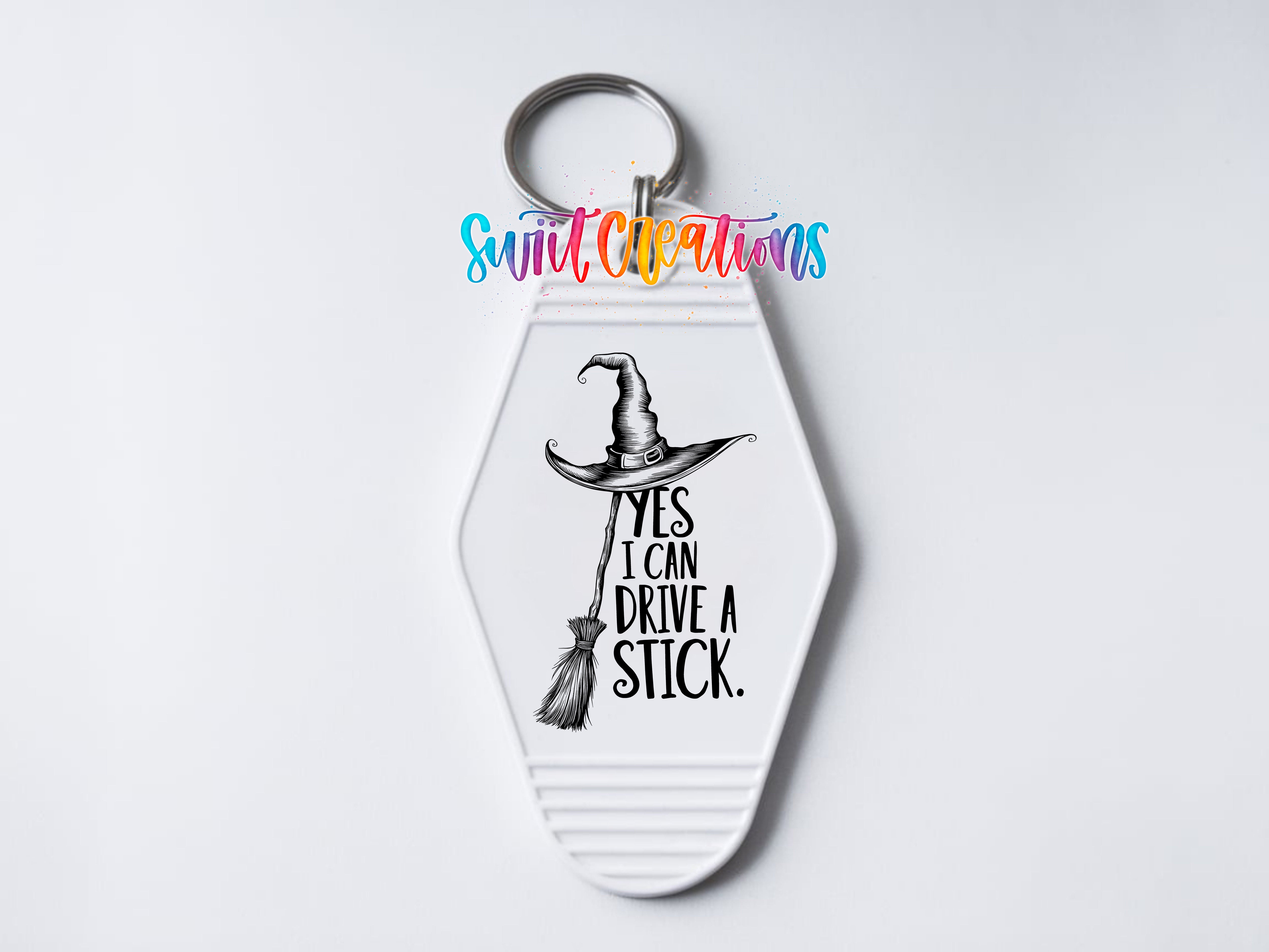 A keychain with a witch's hat and the text "YES I CAN DRIVE A STICK" printed on it.