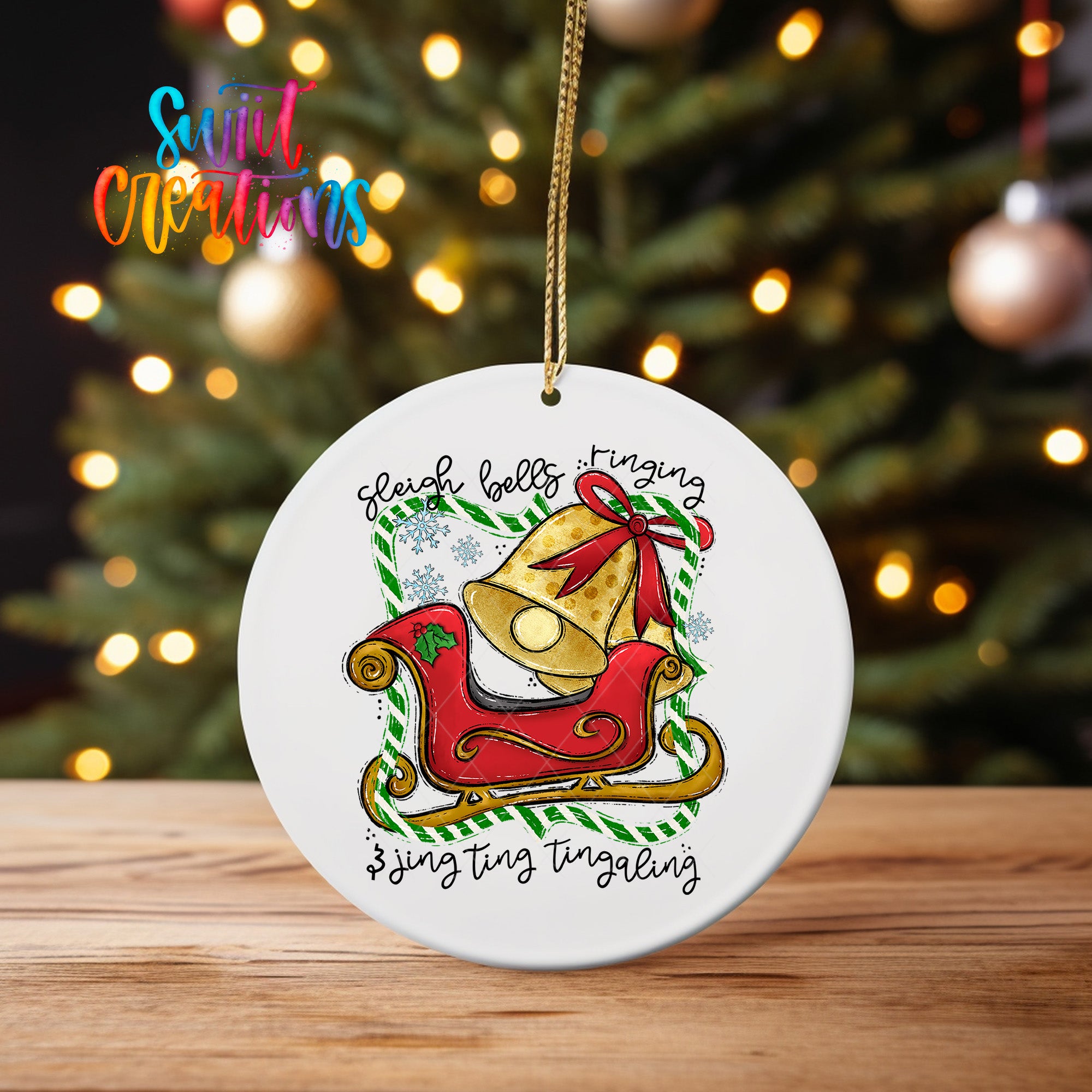 A white ceramic ornament with a red sleigh and a bell, hanging on a string. The ornament features a festive Christmas tree in the background.