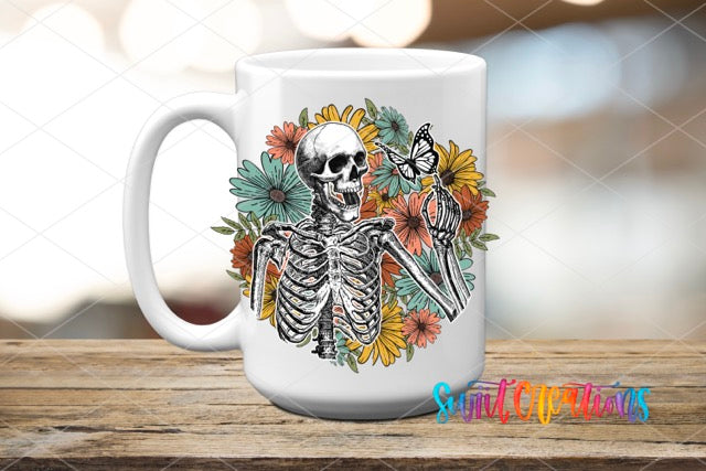 a coffee mug with a skeleton and flowers on it