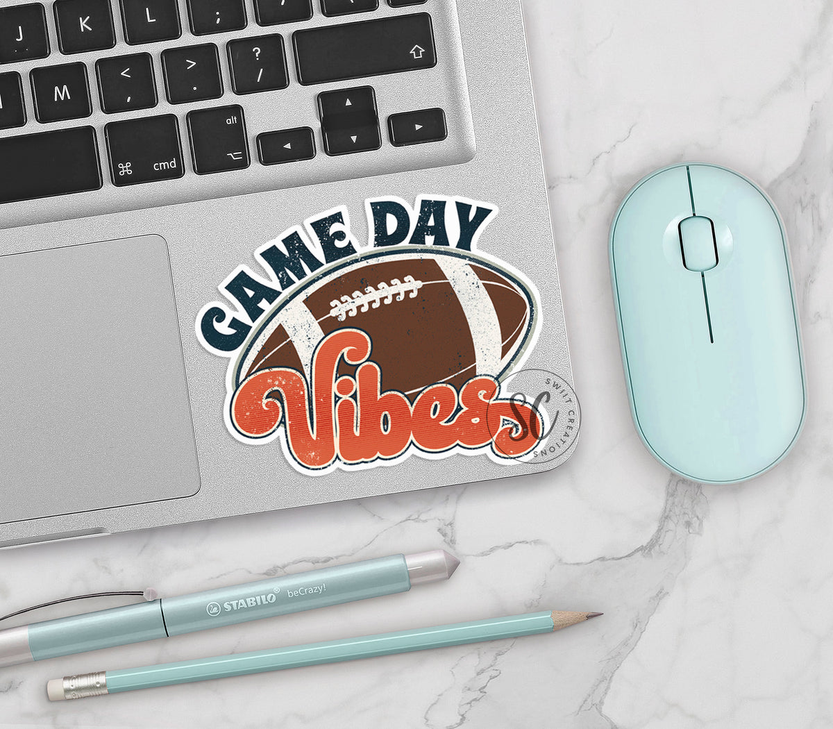 Football Game Day Vibes vinyl sticker on a silver laptop next to a mint mouse and pens