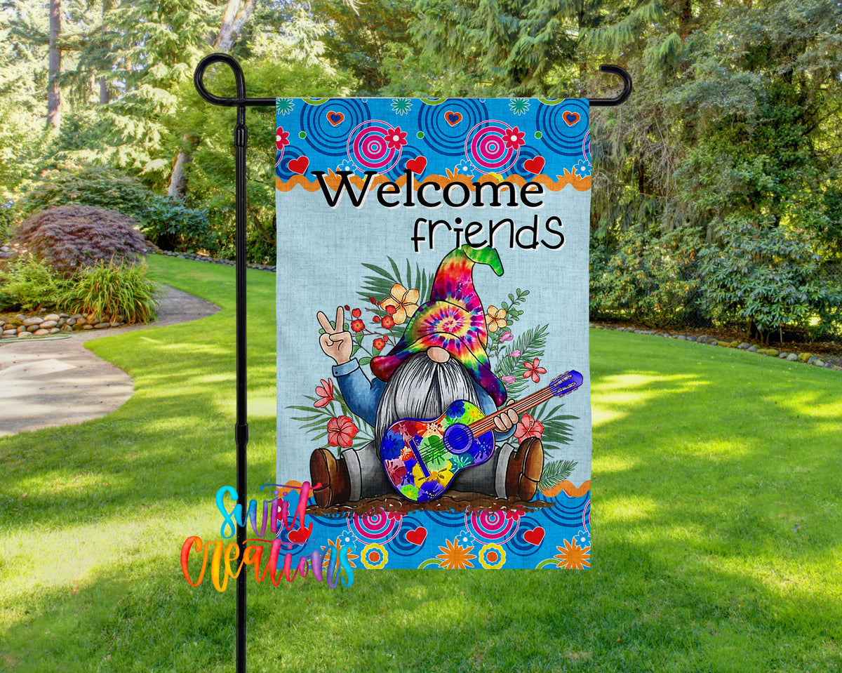 A colorful garden gnome sign with the text "Welcome friends" displayed on it, set against a backdrop of lush greenery and flowers.