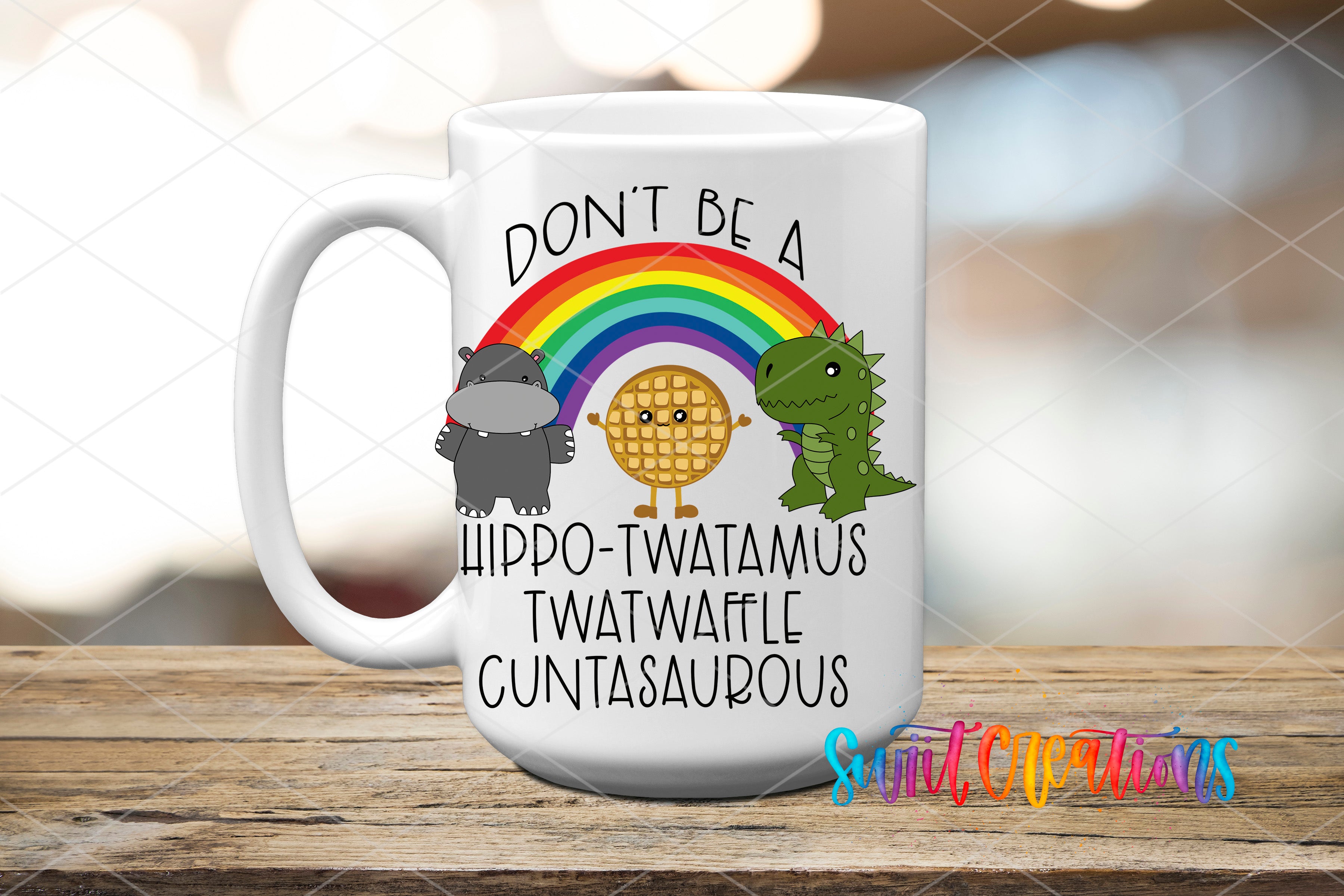 A white ceramic mug with a colorful design featuring a rainbow, a hippopotamus, a dinosaur, and a waffle. The text on the mug reads "DON'T BE A HIPPO TWATAMUS TWATWAFLE CUNTASAUROUS".