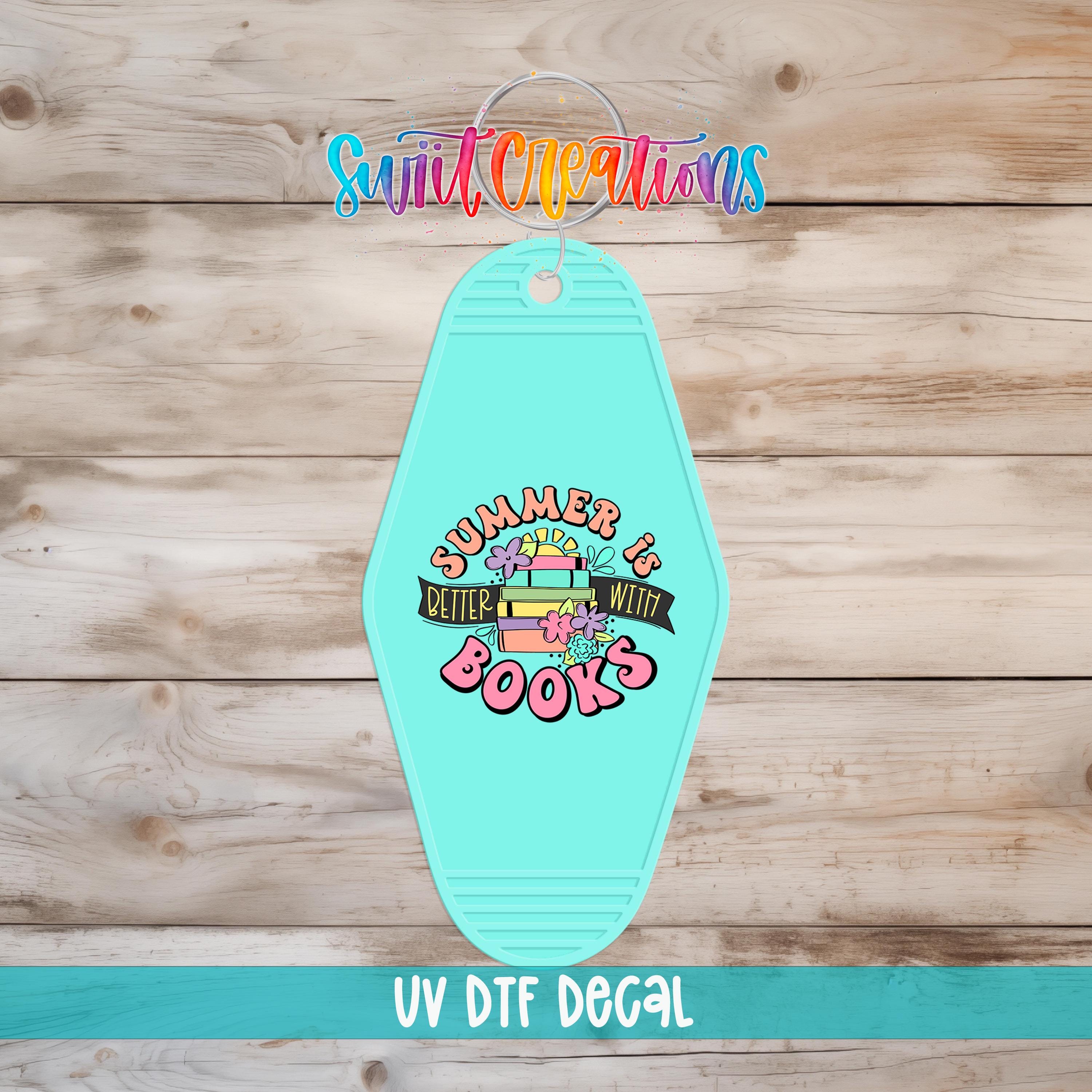A turquoise keychain with a colorful graphic design and text, placed on a wooden surface.