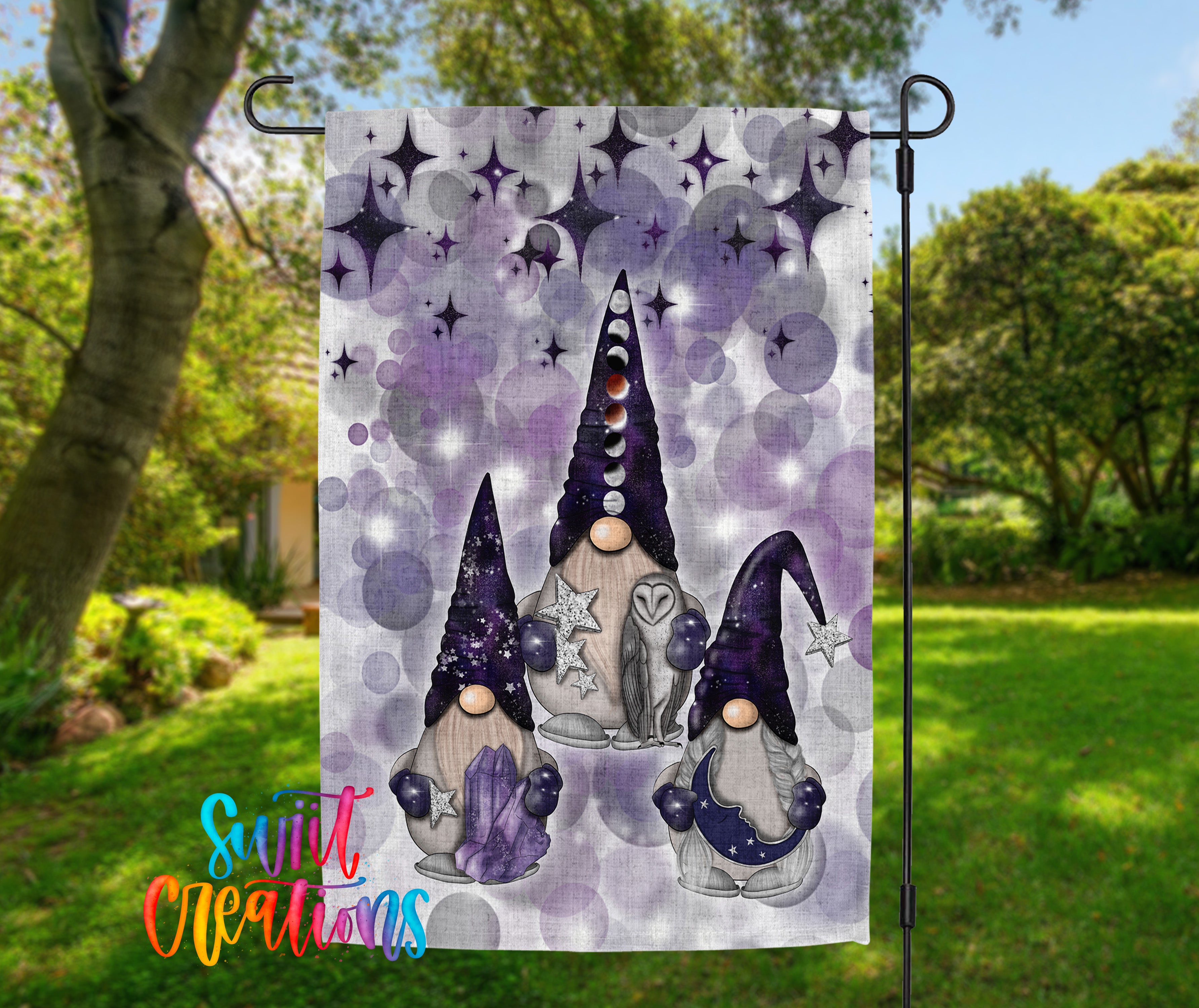 A garden flag featuring three gnomes with purple hats and star-shaped accessories, set against a starry purple and blue background.