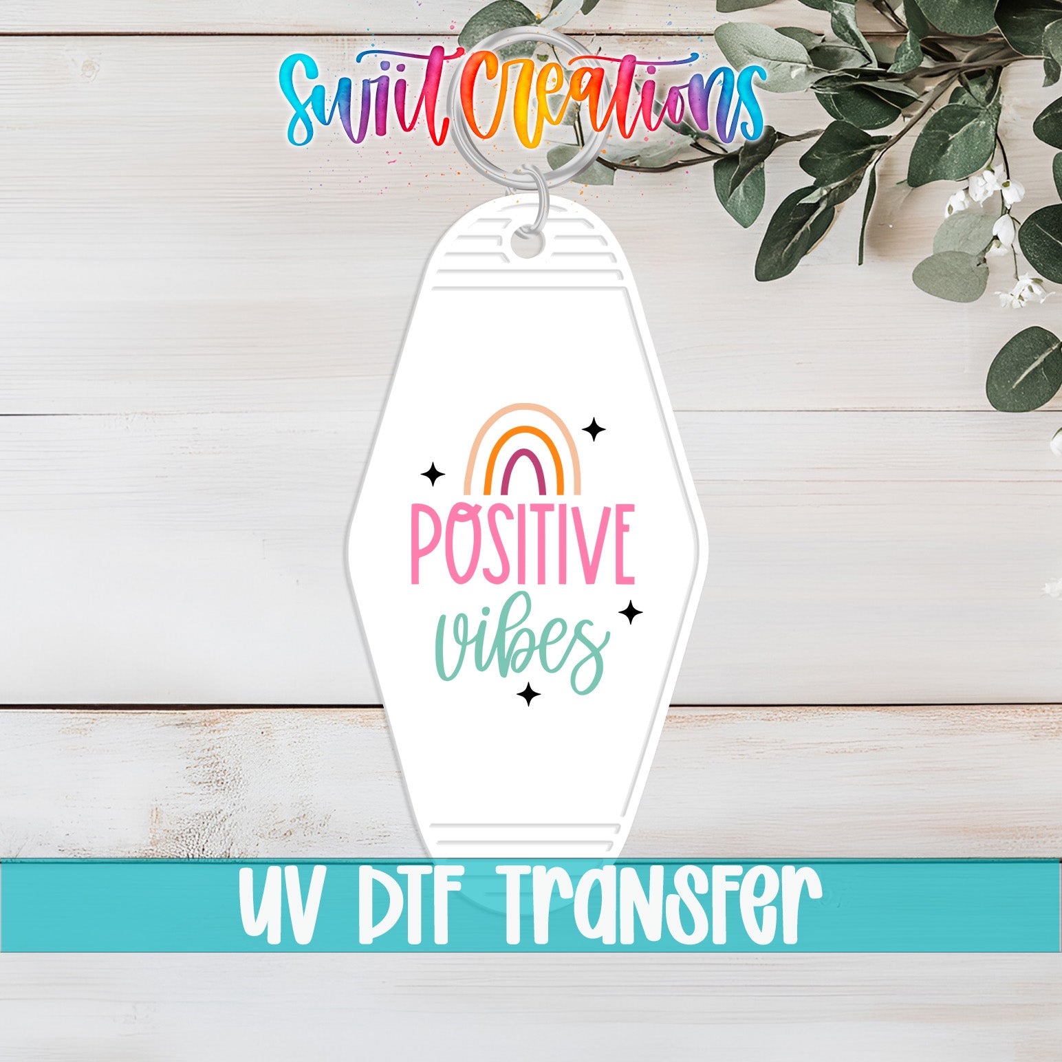 A keychain with a rainbow graphic and the text "POSITIVE VIBES" printed on it, along with a UV DFT Transfer logo.