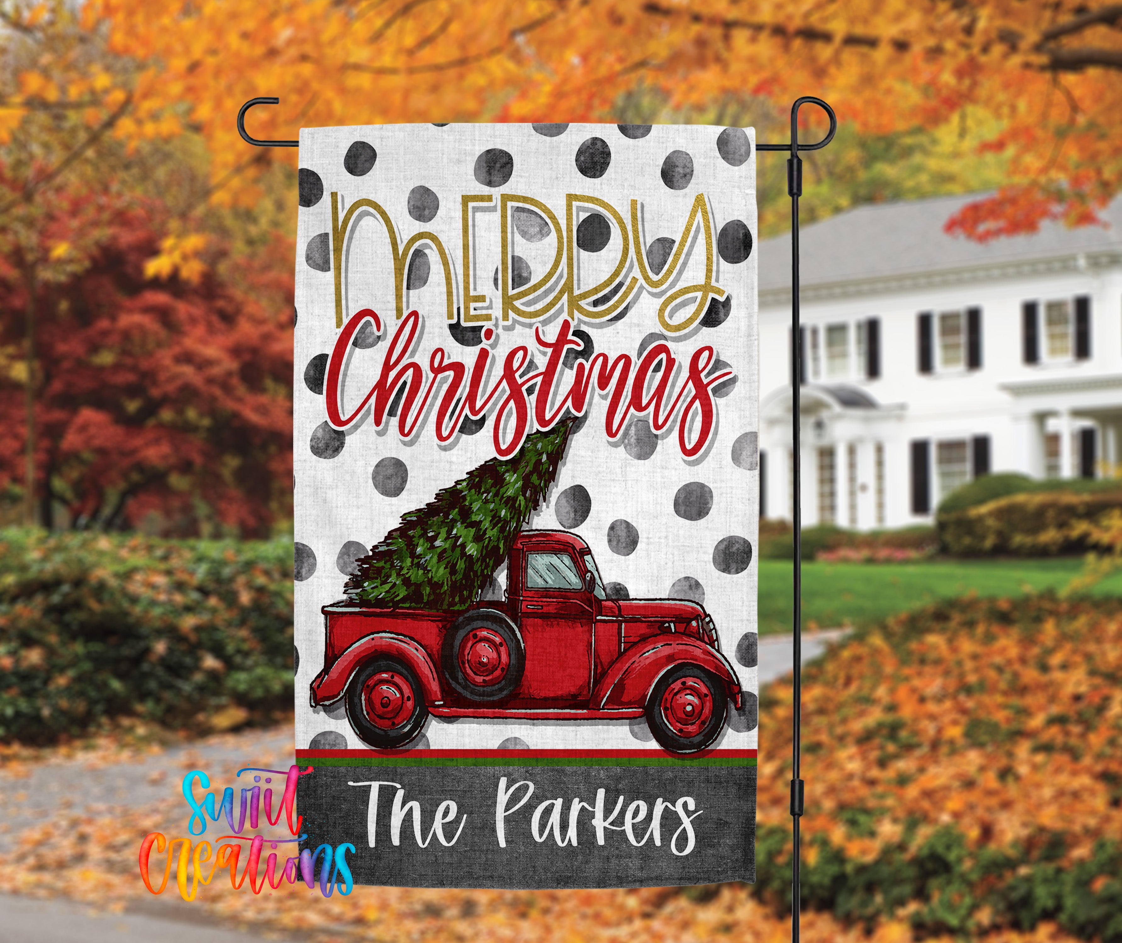 A white flag with a red truck carrying a Christmas tree, with the text "Merry Christmas" and "The Parkers" printed on it. The background features a house and trees with autumn foliage.