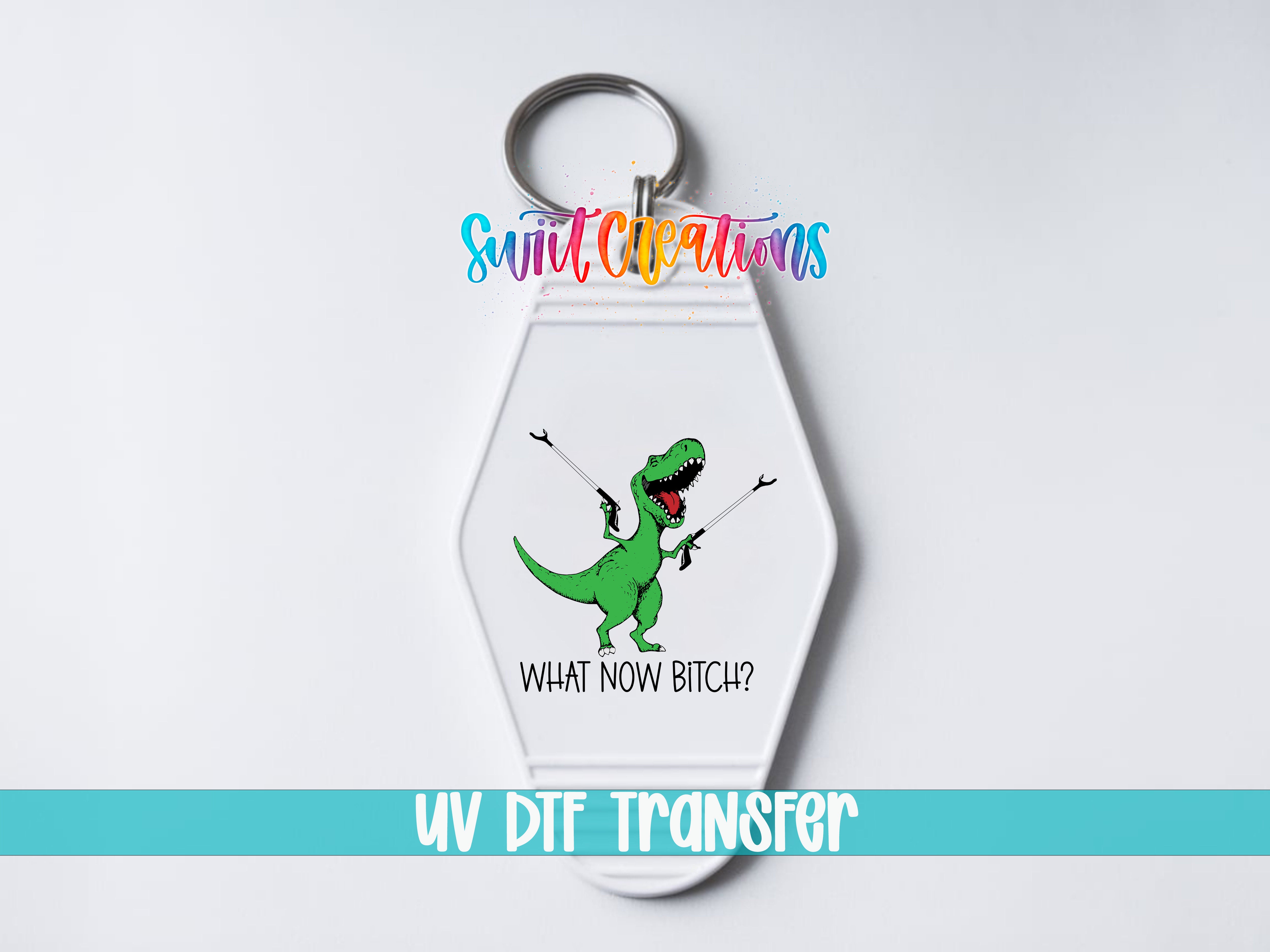 A keychain with a cartoon dinosaur and the text "WHAT NOW BITCH?" printed on it.