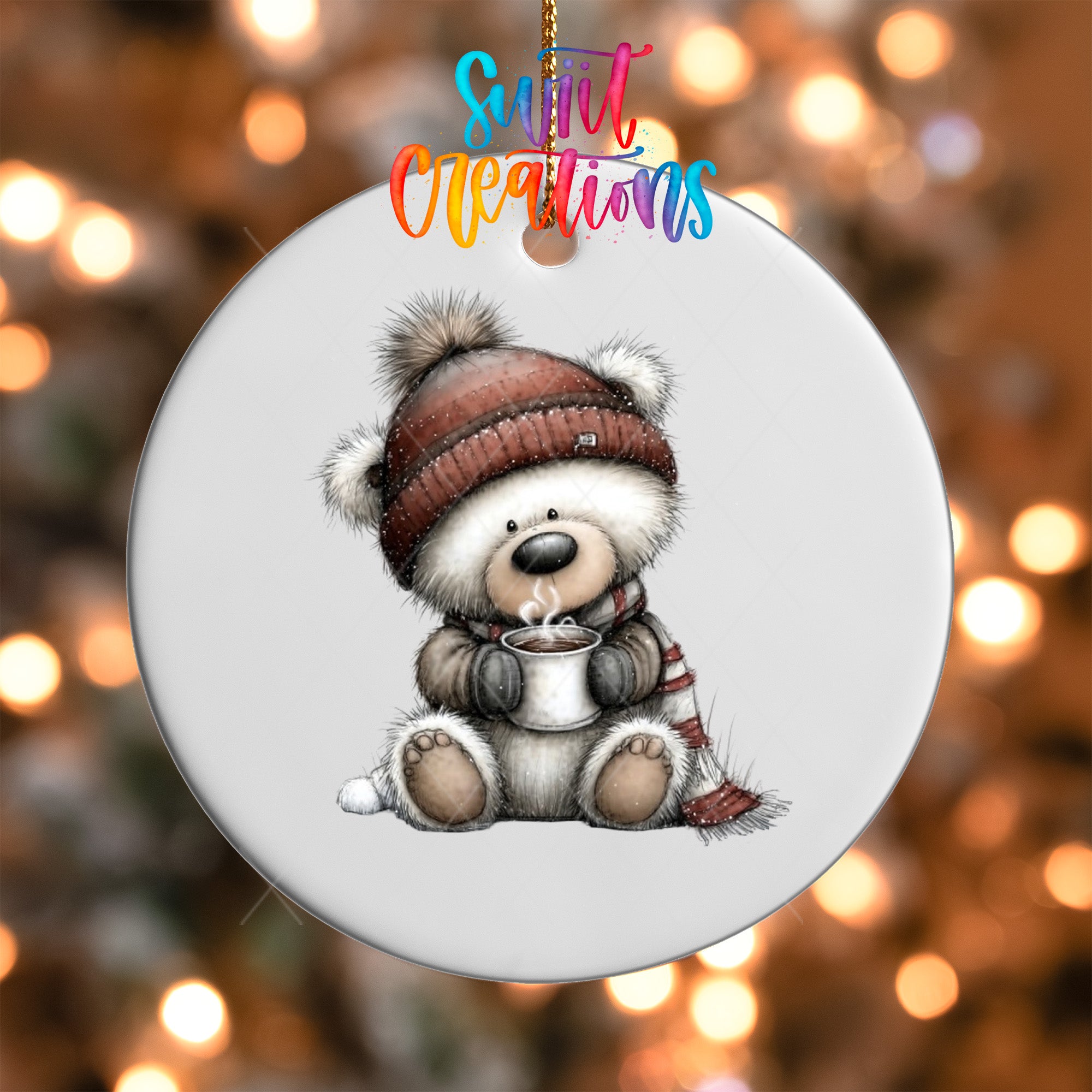 A white ornament with a cute bear wearing a winter hat and scarf, holding a cup of hot chocolate, against a background of colorful lights.
