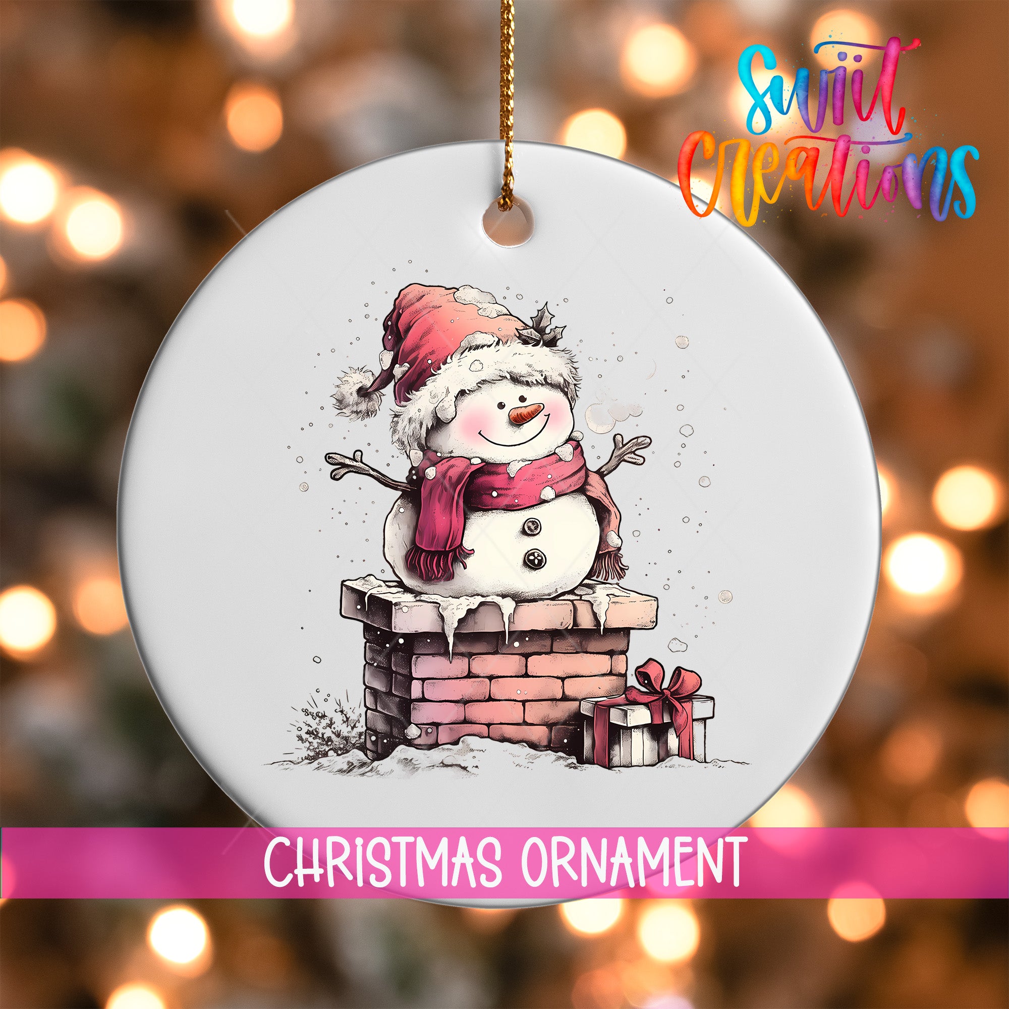 A white Christmas ornament featuring a snowman on a chimney, with a gift box and a red bow on the ground below.