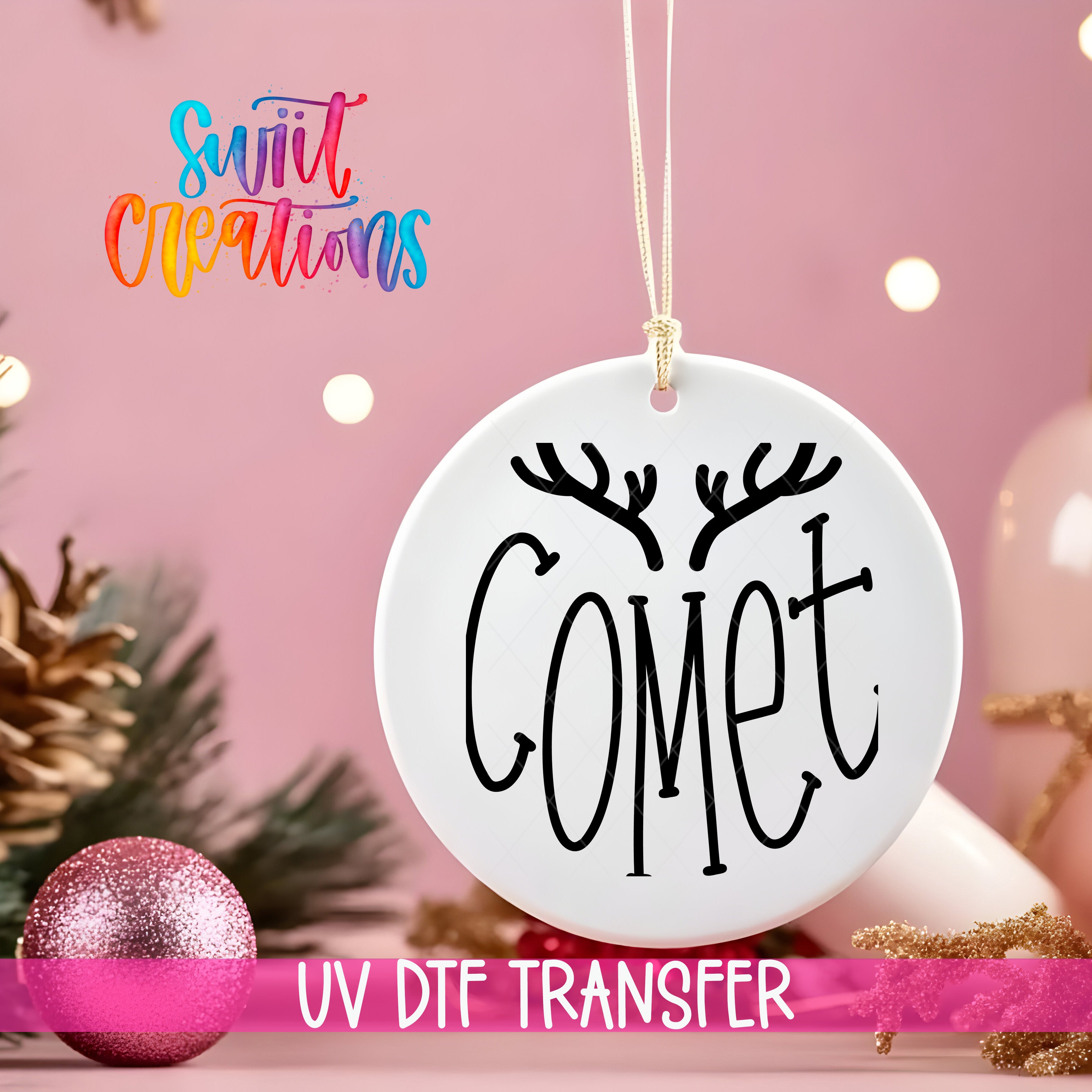 A white ornament with the word "COMET" written on it, hanging on a string against a pink background with Christmas decorations and lights in the background.