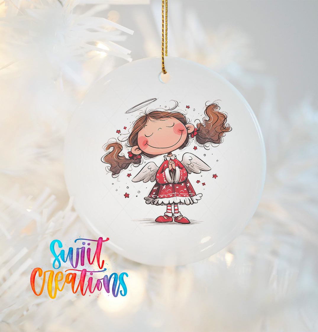 A white ornament featuring a smiling cartoon girl with angel wings, hanging on a Christmas tree.