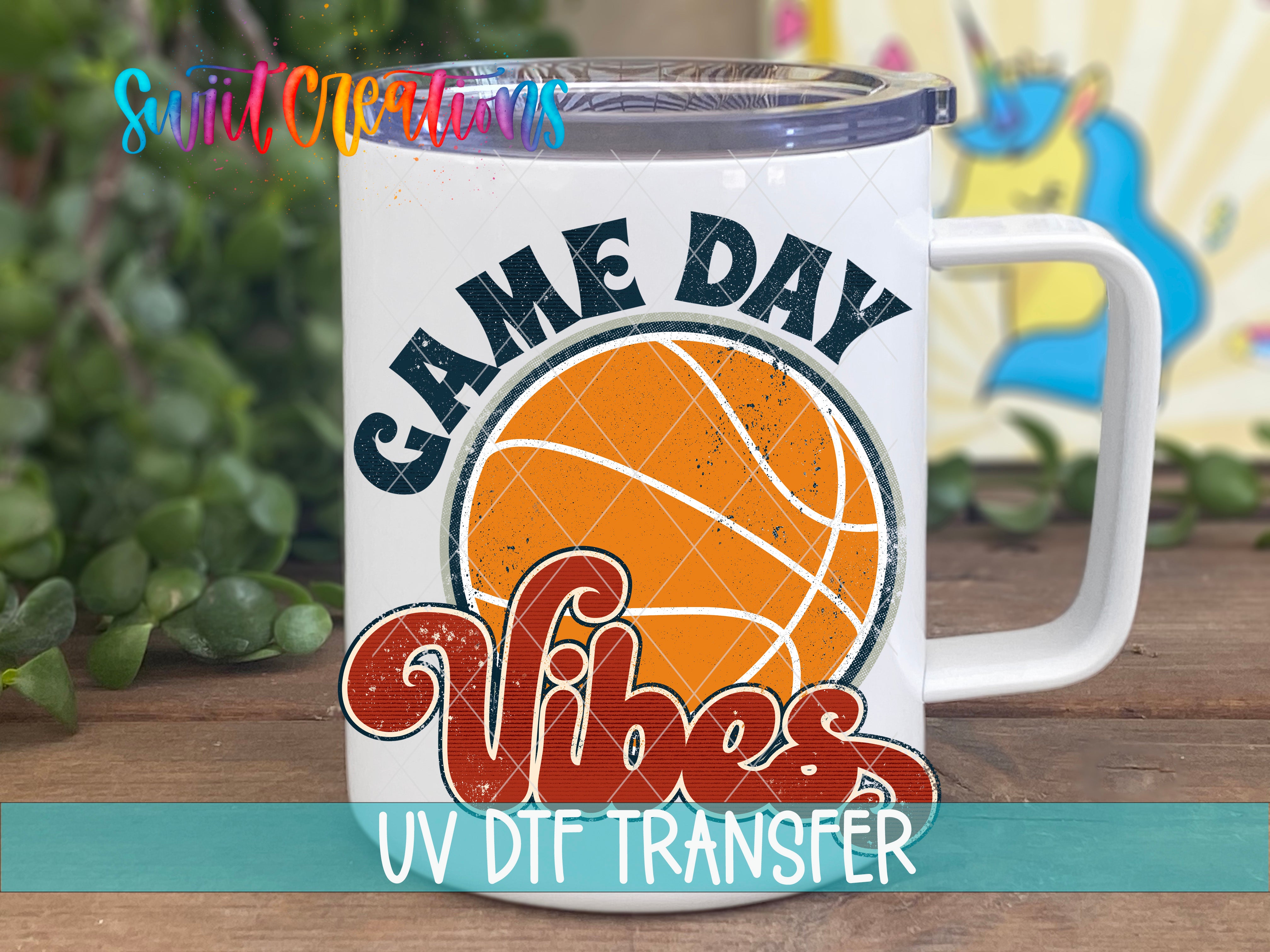 A white mug with a basketball graphic and the text "GAME DAY VIBES" printed on it, placed on a wooden surface.