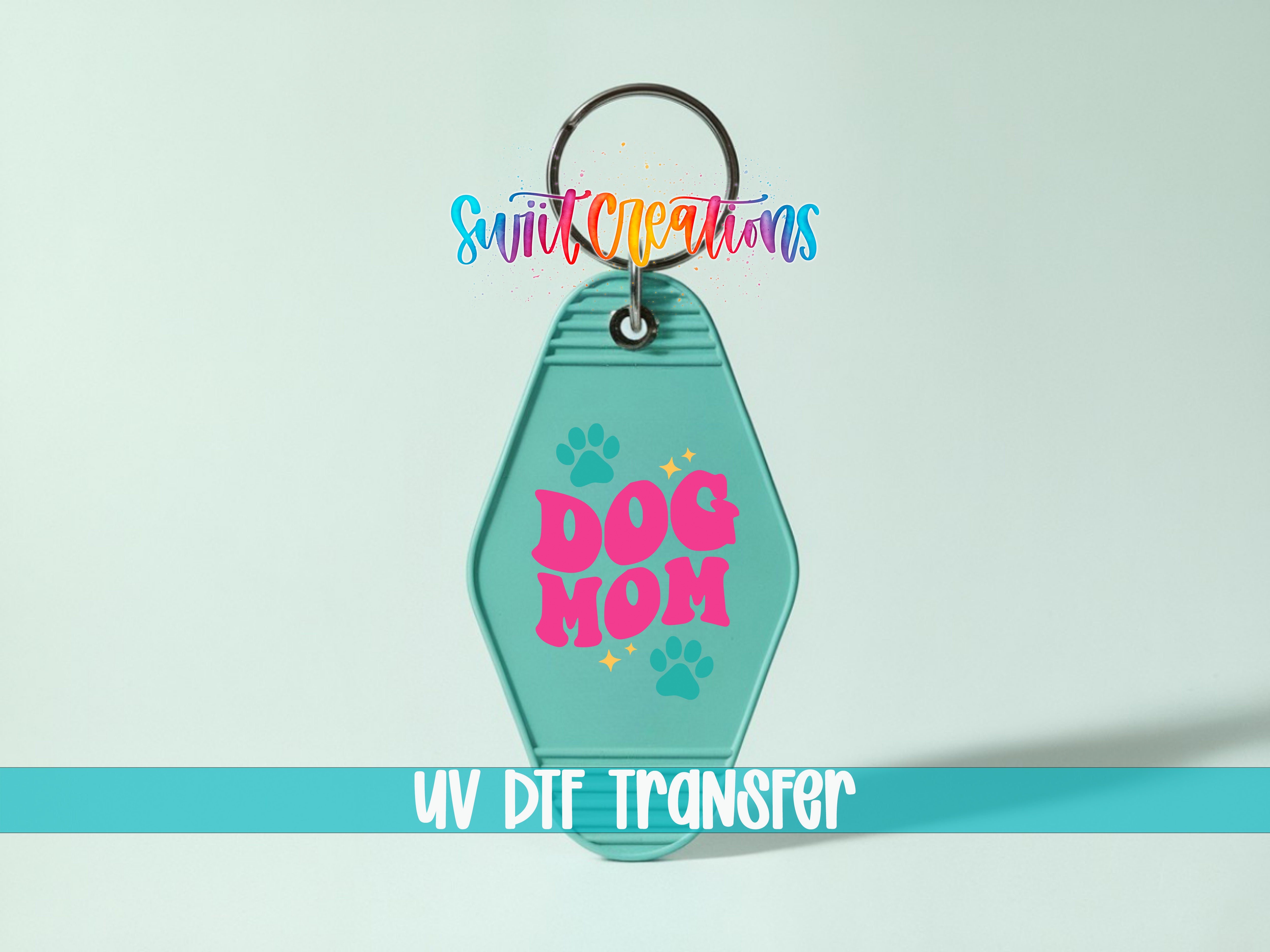 A keychain with the text "DOG MOM" printed on it, along with paw prints and a rainbow-colored tag.