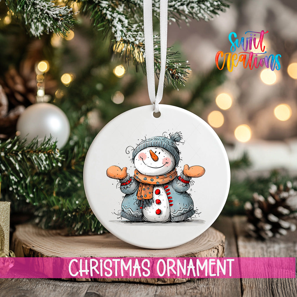 A white Christmas ornament featuring a snowman is hanging from a tree branch, with a blurred background of a decorated Christmas tree and other ornaments.