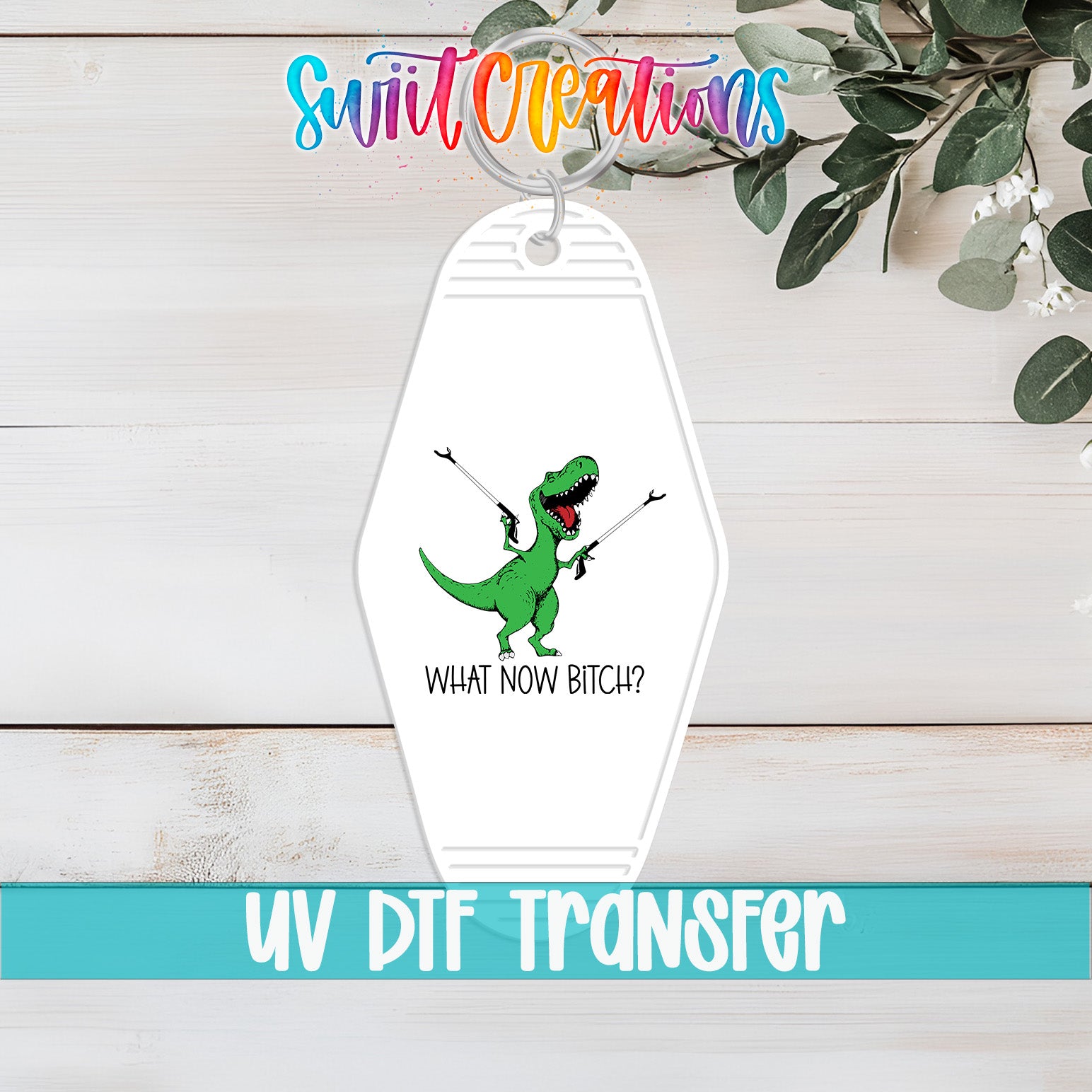 A keychain with a cartoon dinosaur and the text "WHAT NOW BITCH?" printed on it, along with the text "UV DTF Transfer" below it.