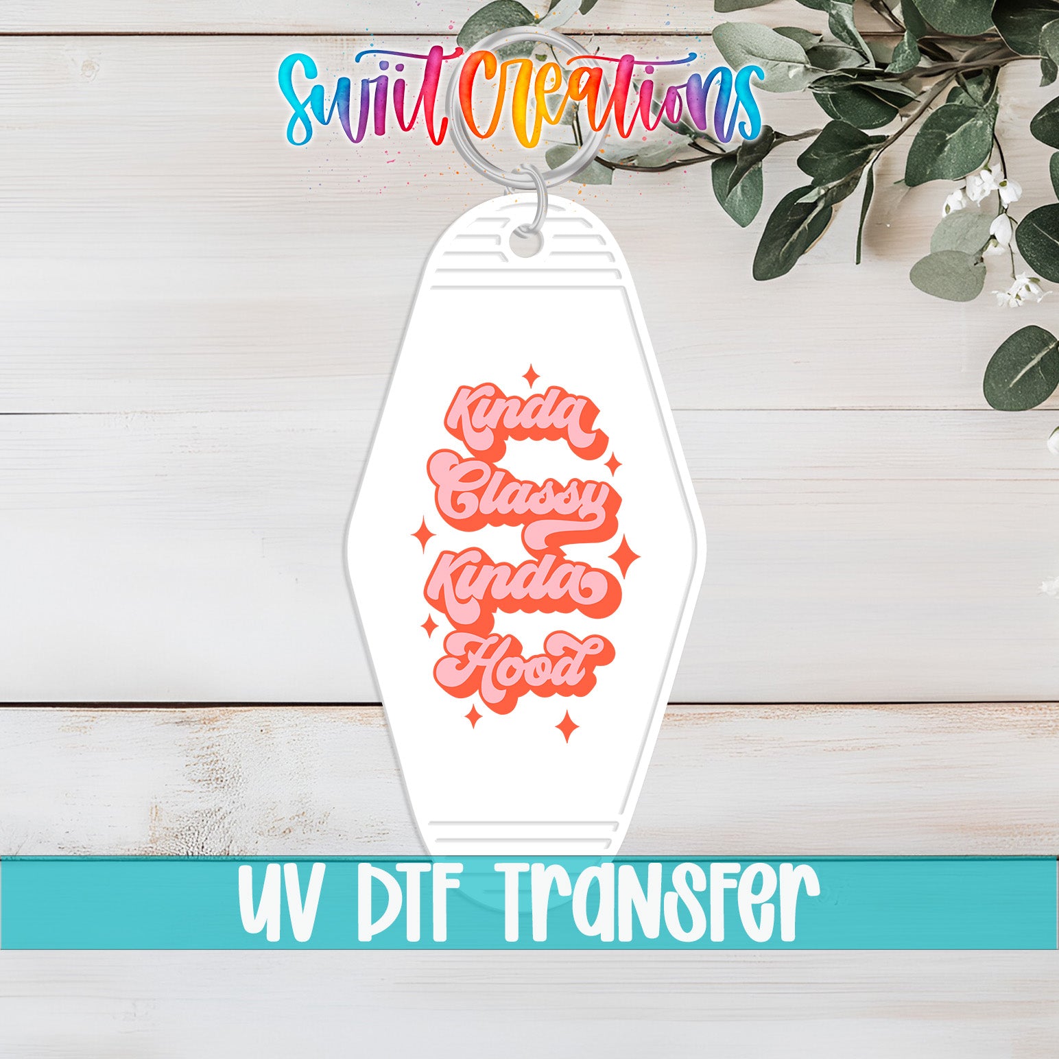 A keychain with a message that says "Kinda Classy Hood" in a stylized font, placed on a wooden surface with some greenery in the background.
