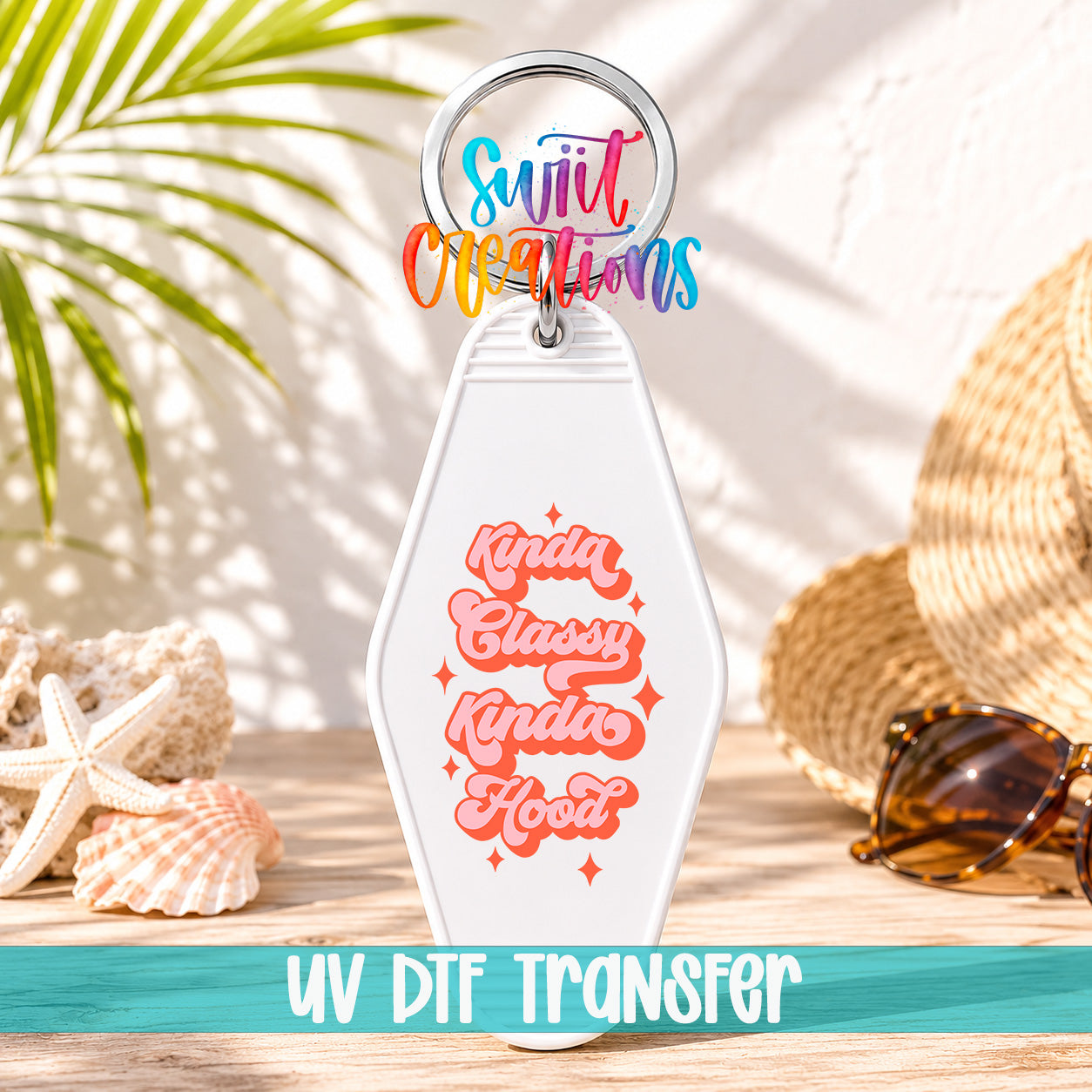 A keychain with a colorful design and text, placed on a wooden surface with sunglasses and a straw hat in the background.