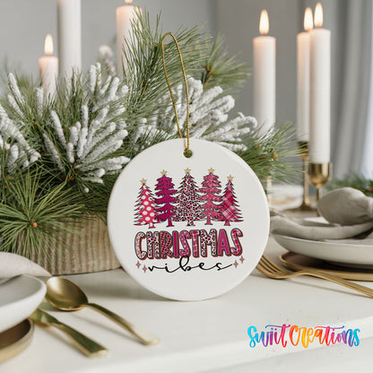 A white Christmas ornament with a leopard print design and the text "Christmas vibes" hangs on a table, surrounded by a floral arrangement and candles.