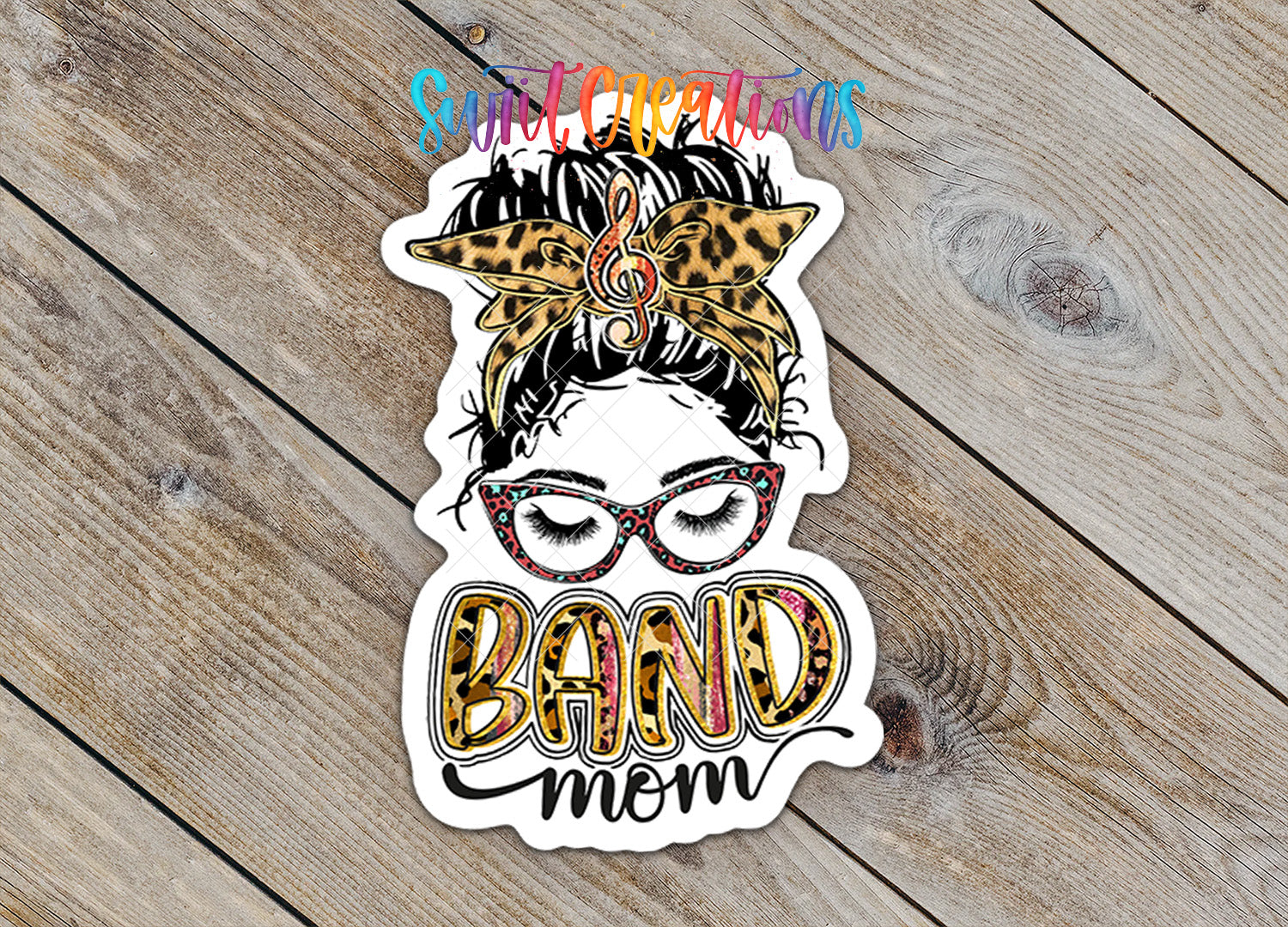 A sticker with a stylized illustration of a woman's face wearing glasses and a leopard print headband, along with the text "BAND MOM" written in a colorful, playful font.