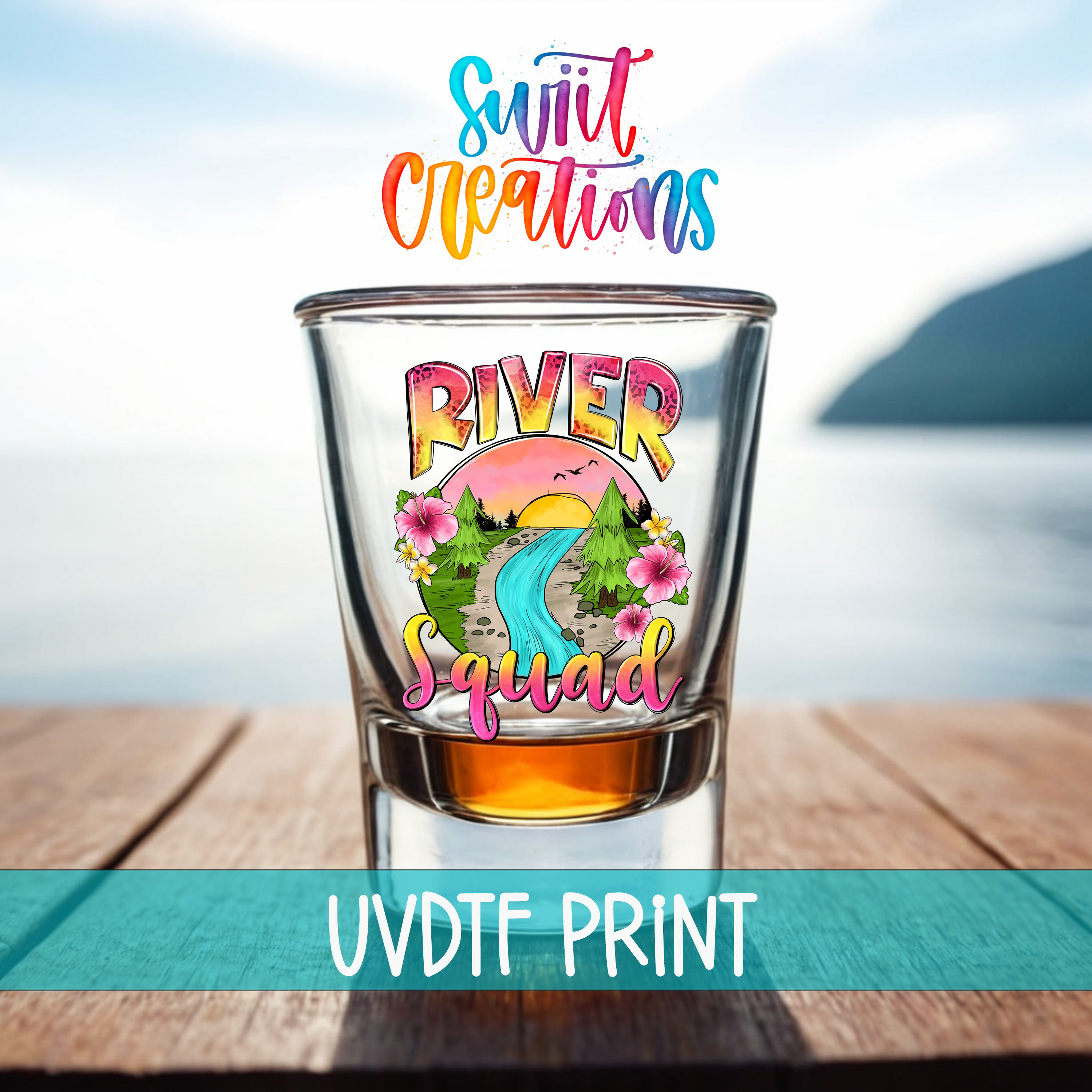 A colorful shot glass with the text "River Squad" printed on it, placed on a wooden surface with a blurred background that includes a body of water and mountains.