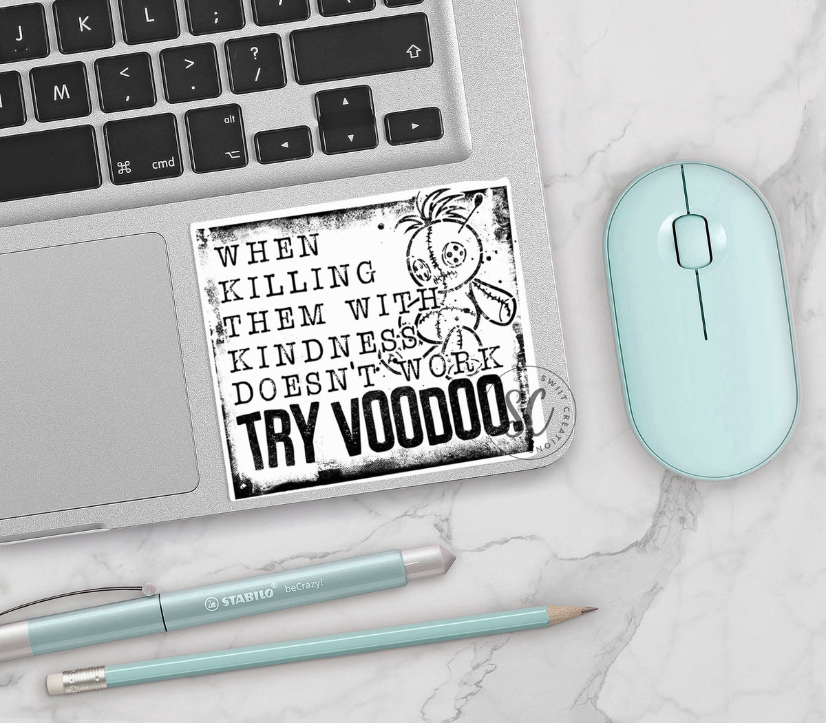 Try Voodoo vinyl sticker on a silver laptop next to a mint mouse and pens