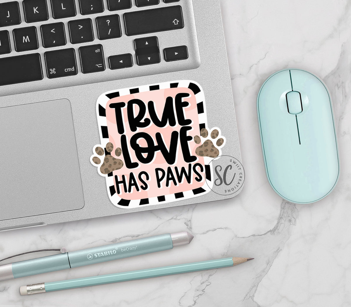 True Love Has Paws vinyl sticker on a silver laptop next to a mint mouse and pens