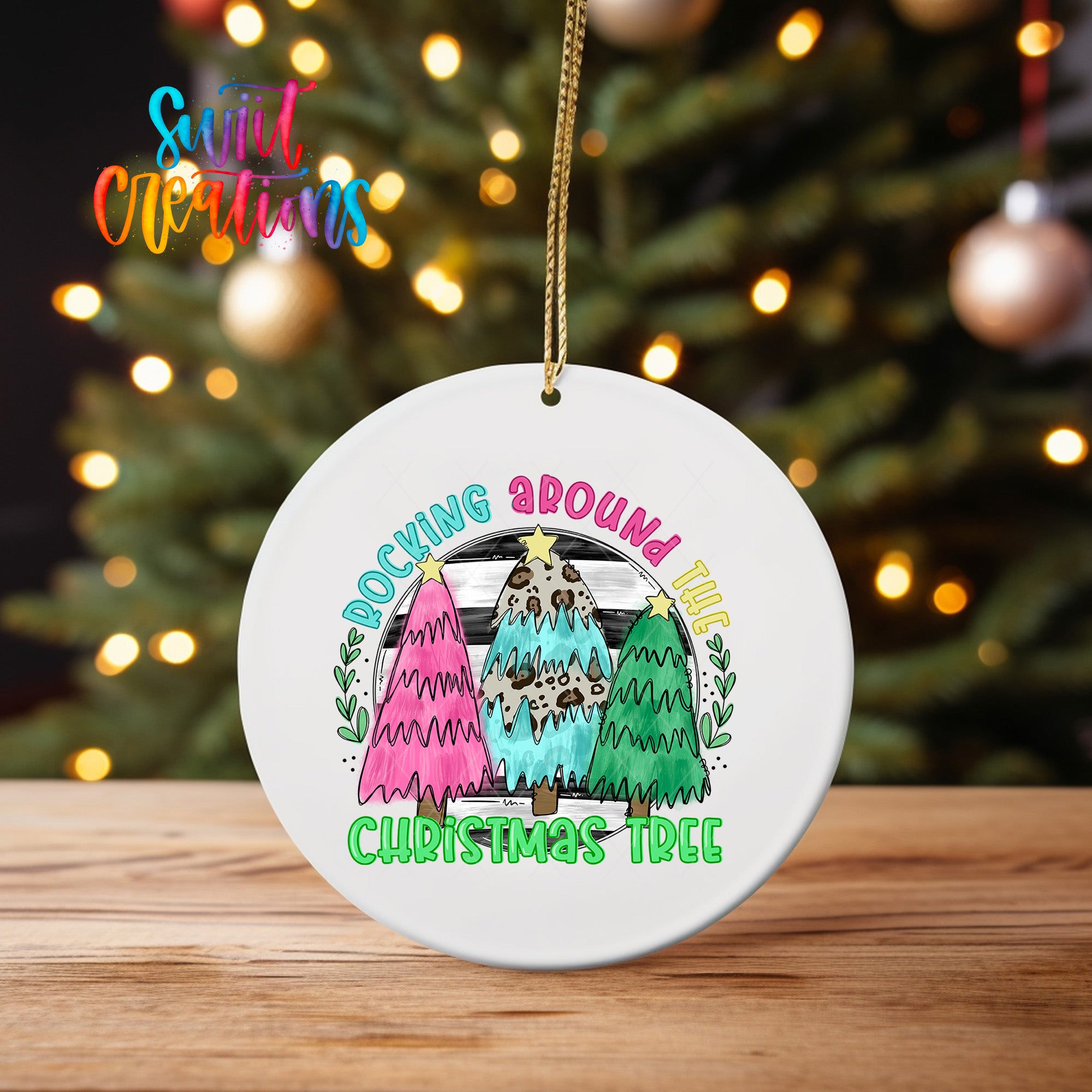 A white ceramic ornament with a colorful illustration of three Christmas trees and the text "Rocking around the Christmas tree" hanging from a string.