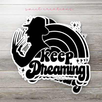 Stack of Keep Dreaming glossy stickers on a gray wood table