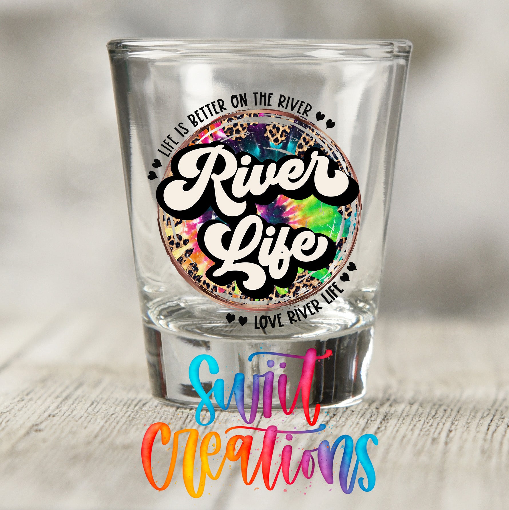 a shot glass with a colorful, tie-dye design and text that reads "River Life Love River Life".
