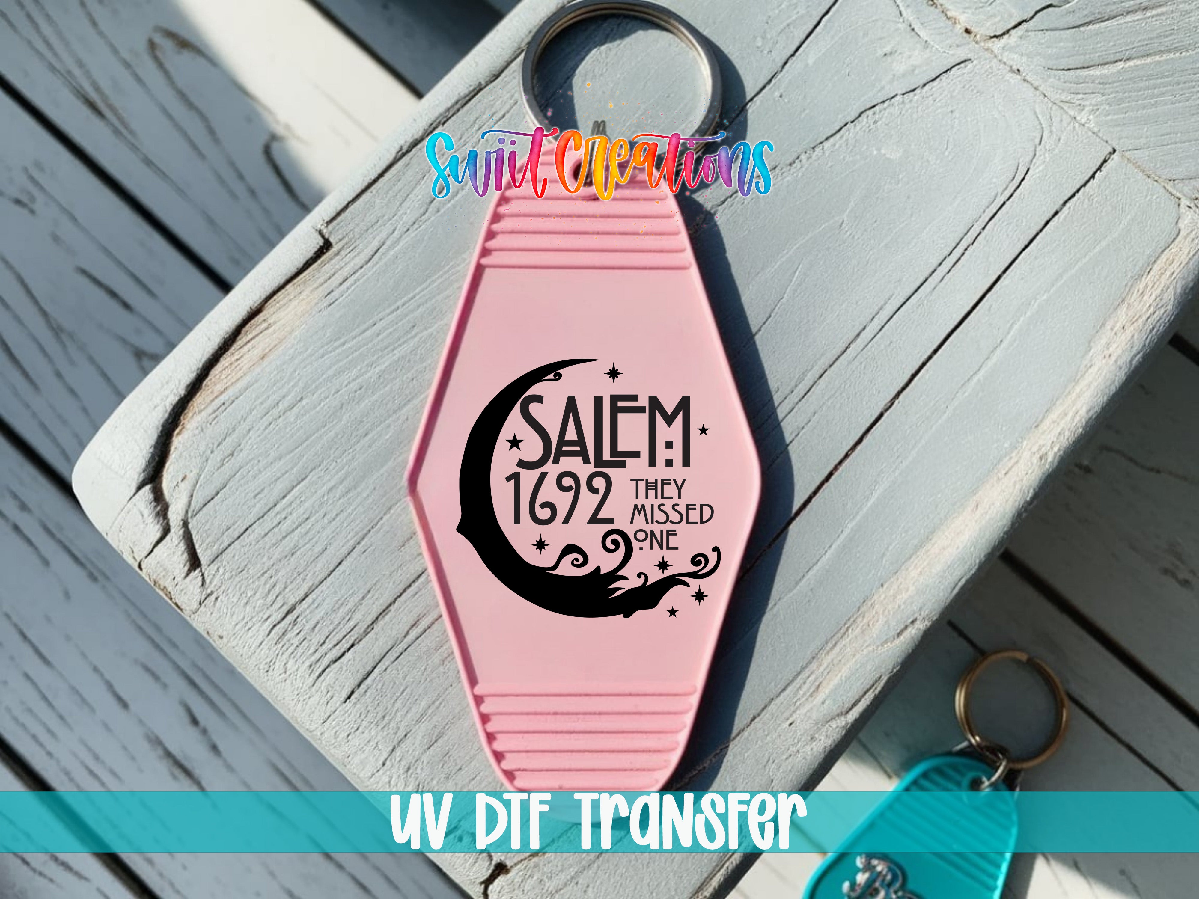 A pink keychain with a black crescent moon and star design, along with text that reads "SALEM 1692 THEY MISSED ONE".