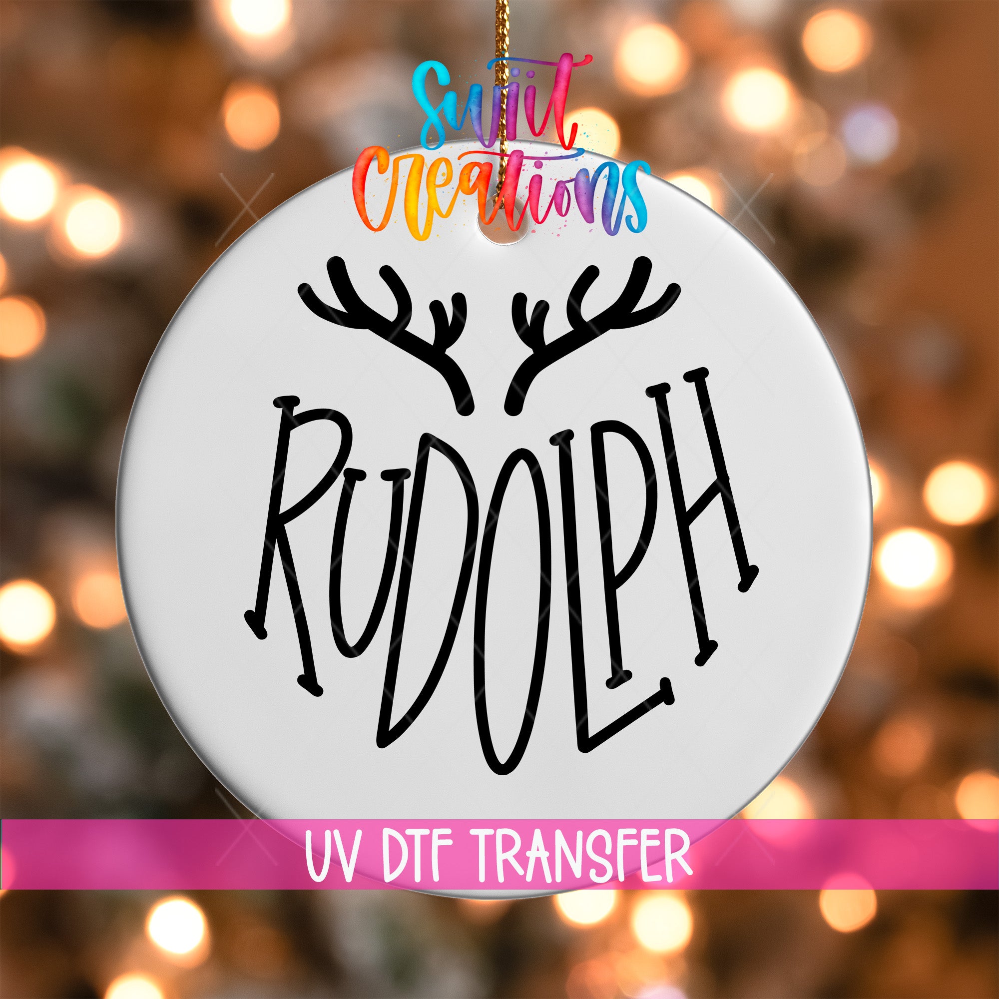 A white ornament with the word "RUDOLPH" written on it, hanging against a background of colorful lights.