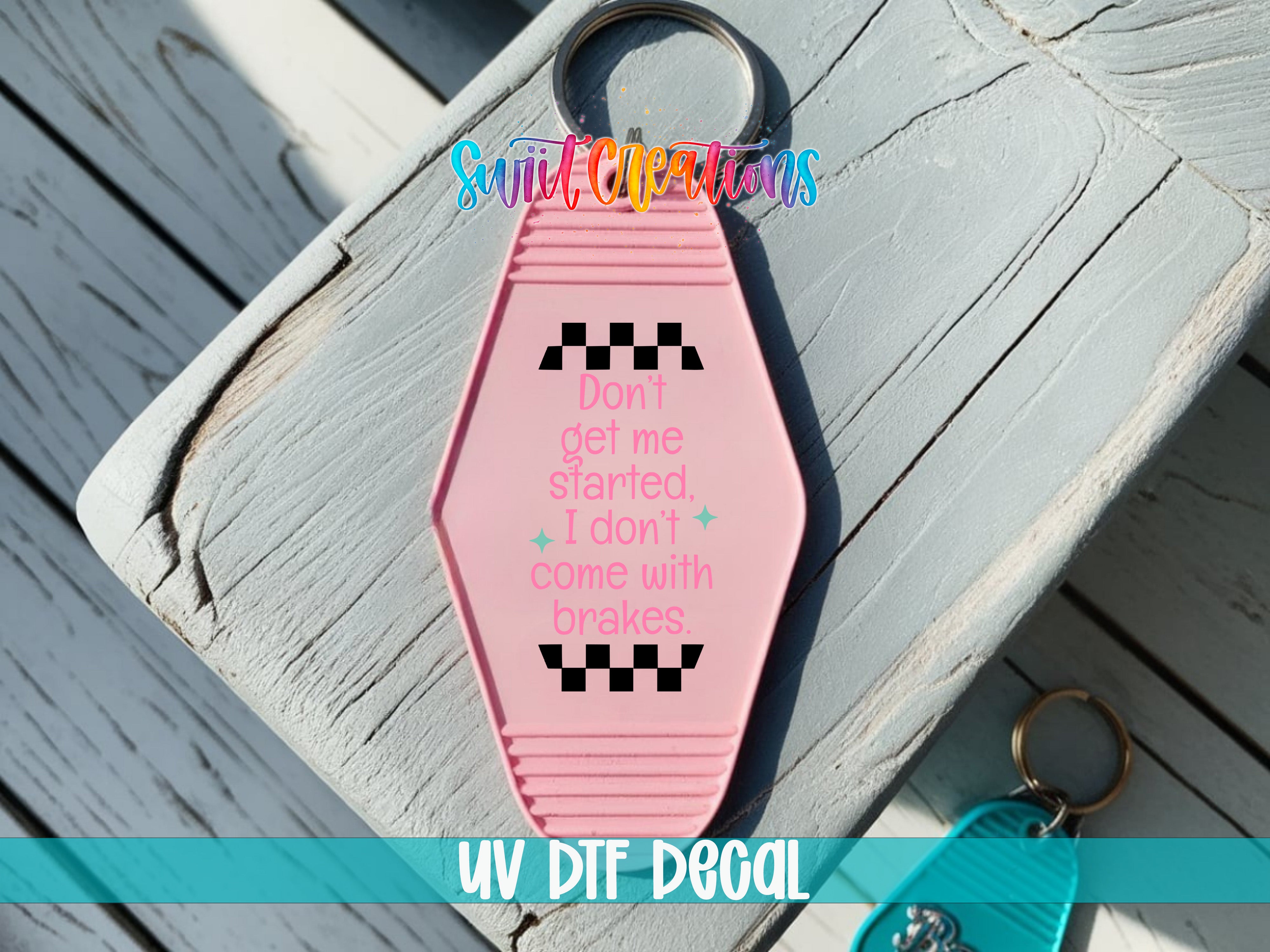 A pink keychain with a message printed on it, placed on a wooden surface.