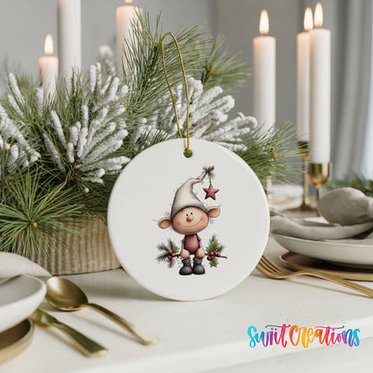 A white ceramic ornament featuring a cartoon elf is displayed on a table, surrounded by a festive arrangement of pine branches and candles.