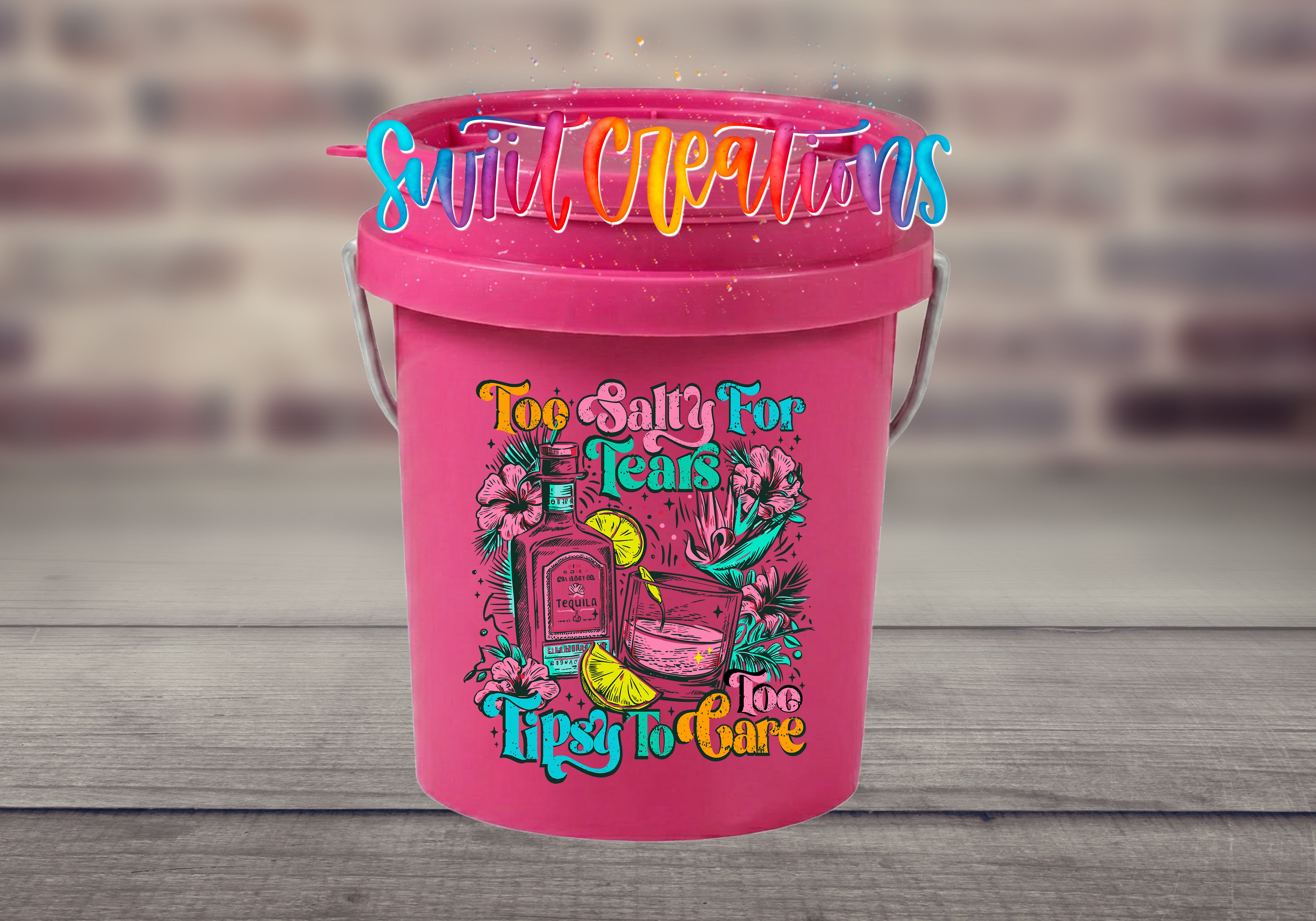 A pink bucket with a colorful graphic and text on it, placed on a wooden surface.