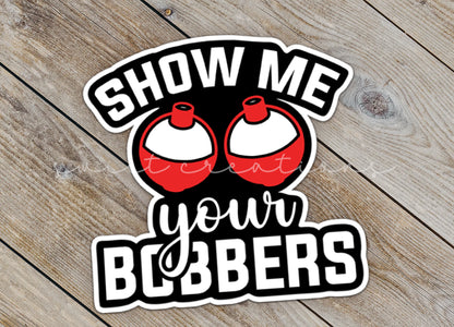 Close-up of the Show Me Your Bobbers sticker on rustic wood
