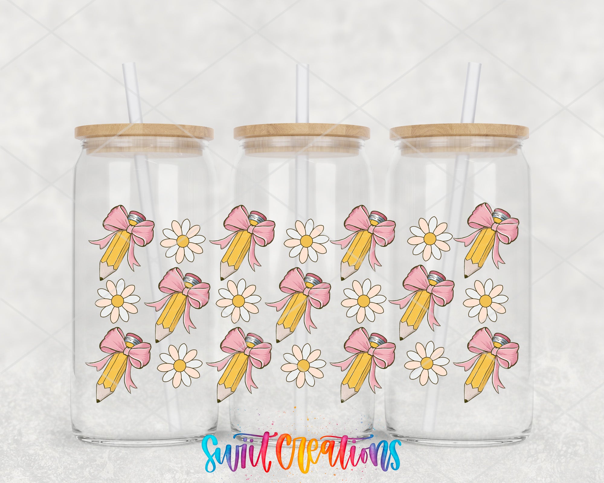 Three glass tumblers with wooden lids, each containing a straw. The tumblers are decorated with a repeating pattern of pink and yellow pencils with bows and white daisies.