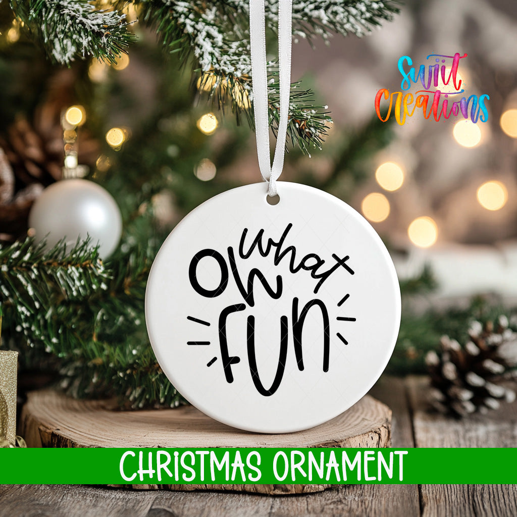 A white Christmas ornament with the text "What's fun" written on it, hanging from a tree branch.
