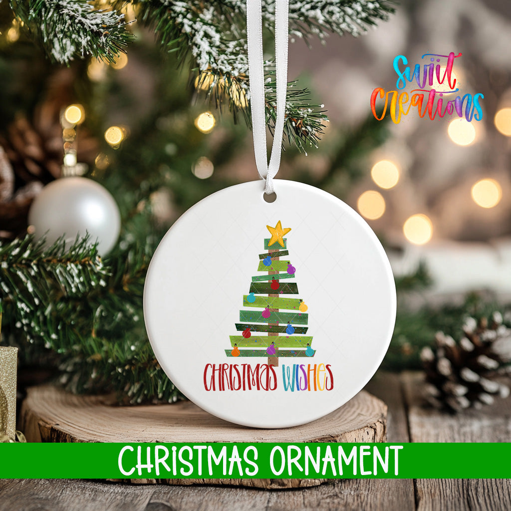 A white Christmas ornament with a tree design and the text "Christmas Wishes" hangs on a tree branch, surrounded by other Christmas decorations and lights.