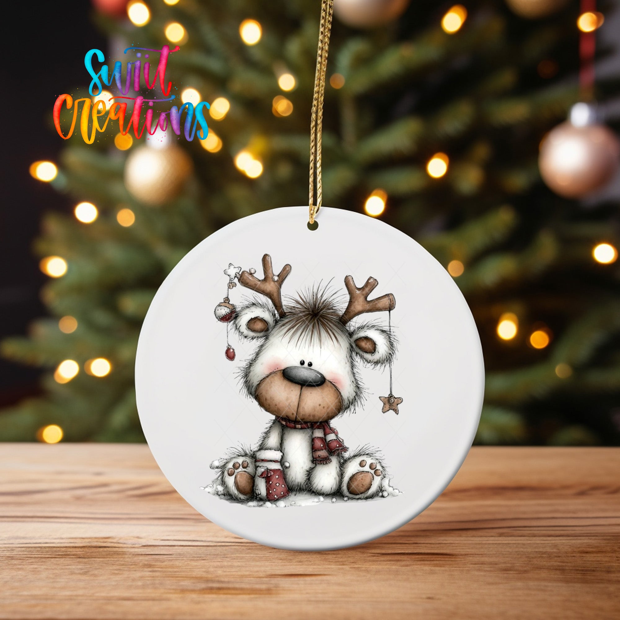 A white ceramic ornament featuring a cartoon reindeer with antlers and a star, sitting on a wooden surface in front of a blurred Christmas tree with twinkling lights.