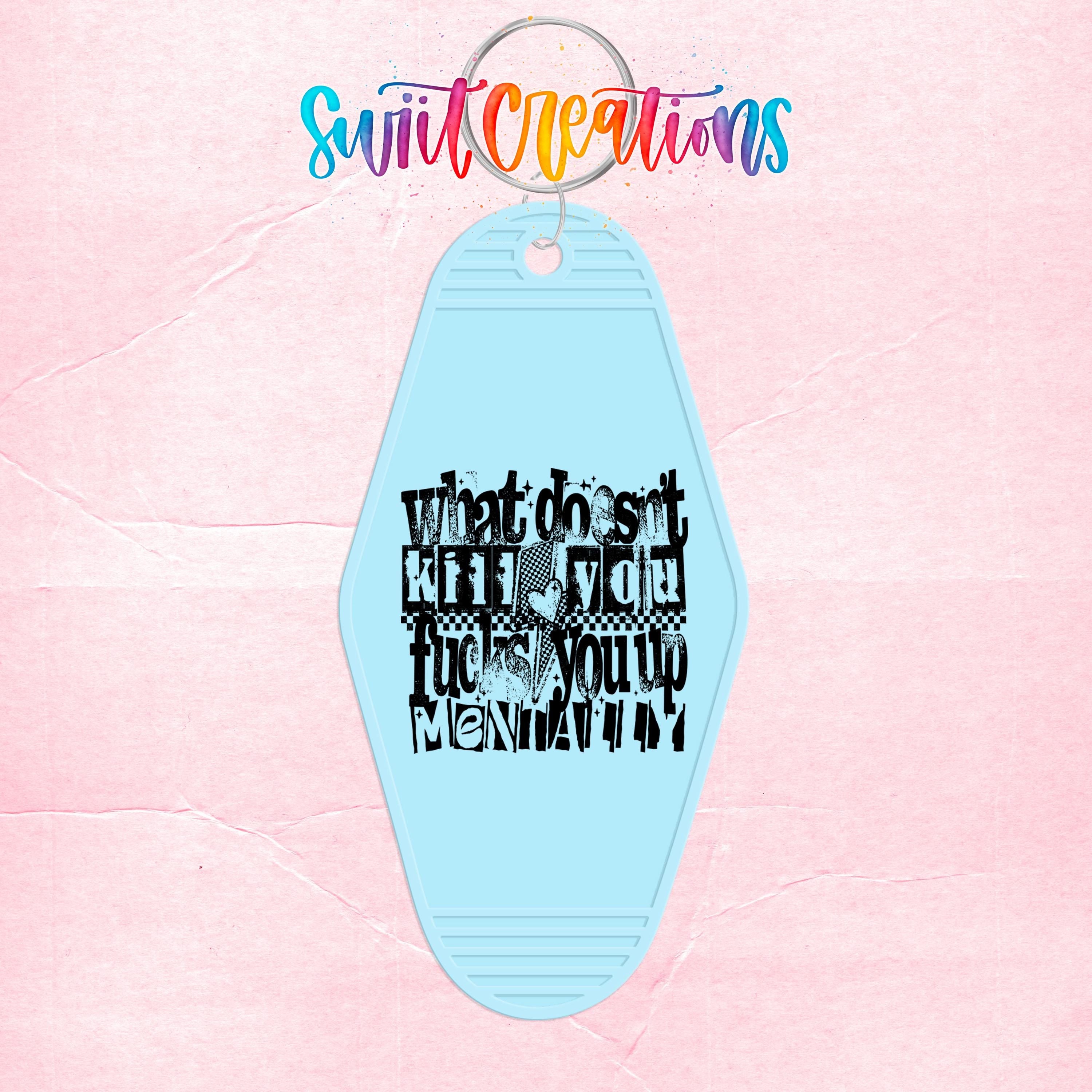 A light blue keychain with a black text design on it, against a pink background.