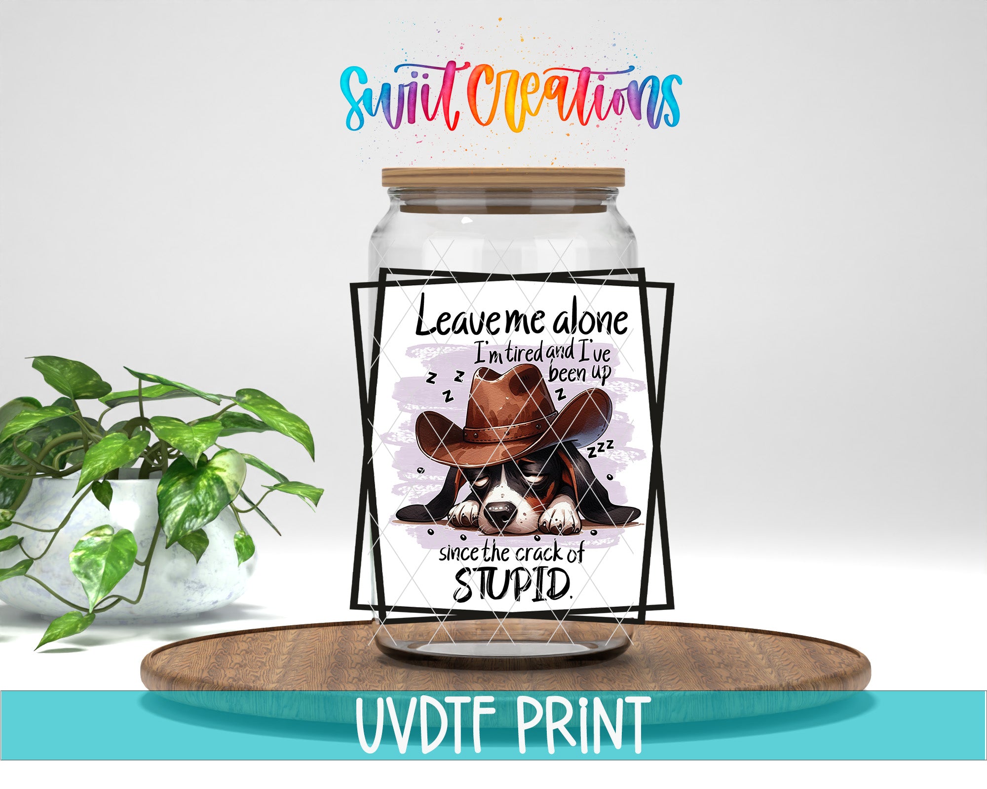 a jar with a label that says "Leave me alone I'm tired and I've been up since the crack of stupid" and a picture of a dog wearing a cowboy hat. The jar is placed on a wooden surface, and there is a potted plant in the background.